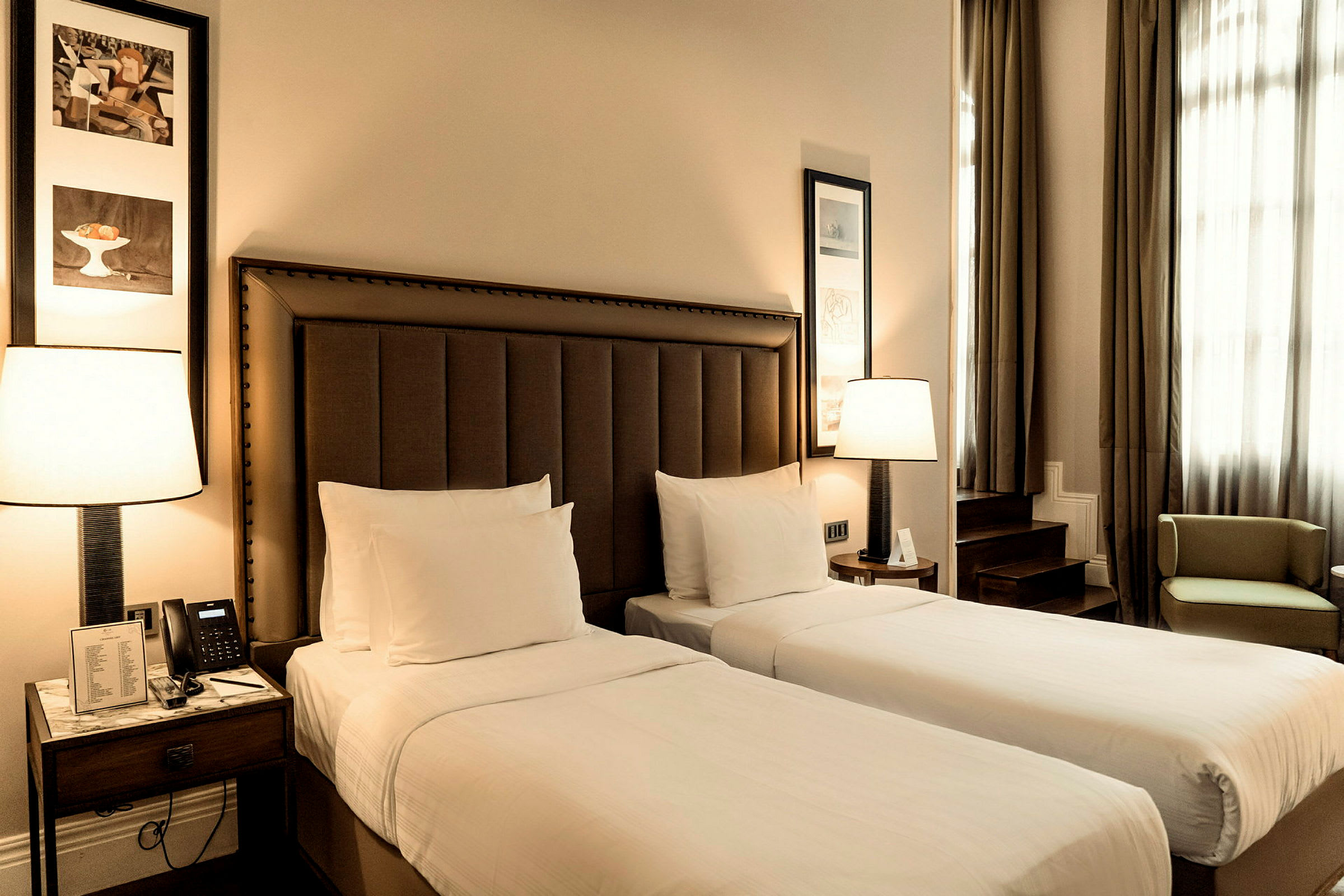 Två enkelsängar med vita lakan i ett stilfullt hotellrum. (AI-genererad text)