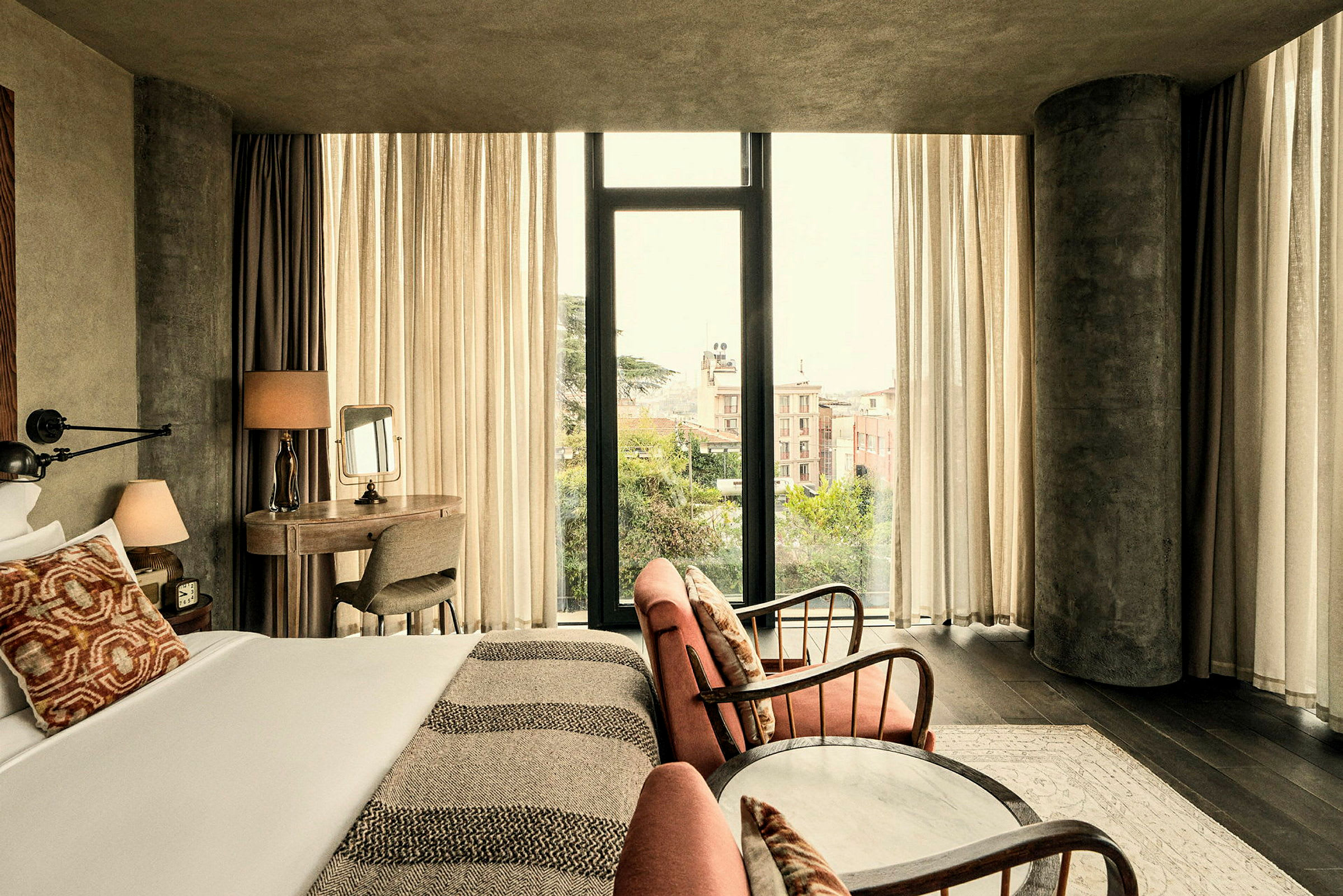 Ett hotellrum med stora fönster, en säng med kuddar och en sittgrupp. (AI-genererad text)