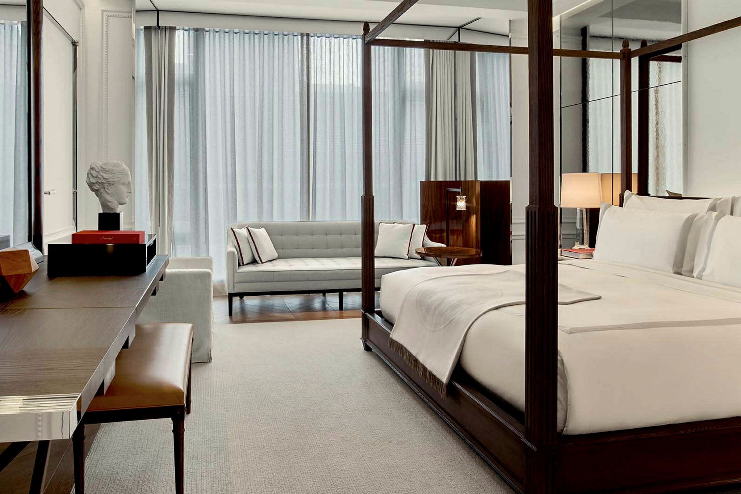 Ett elegant hotellrum med en himmelssäng, soffa och skrivbord. (AI-genererad text)