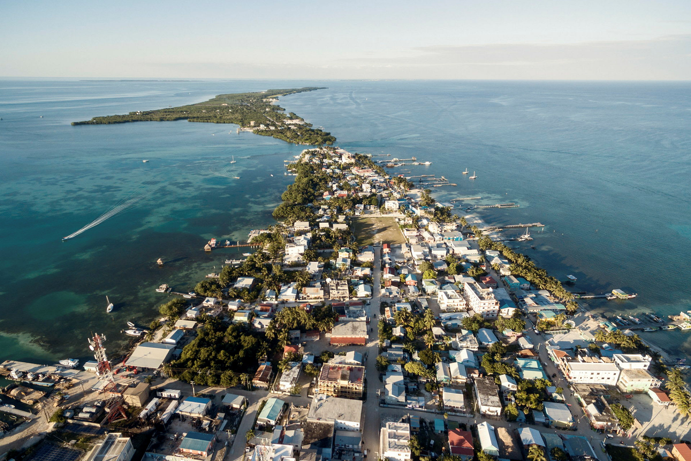 Flygfoto över en stad vid en kust med havet och horisonten i bakgrunden. (AI-genererad text)