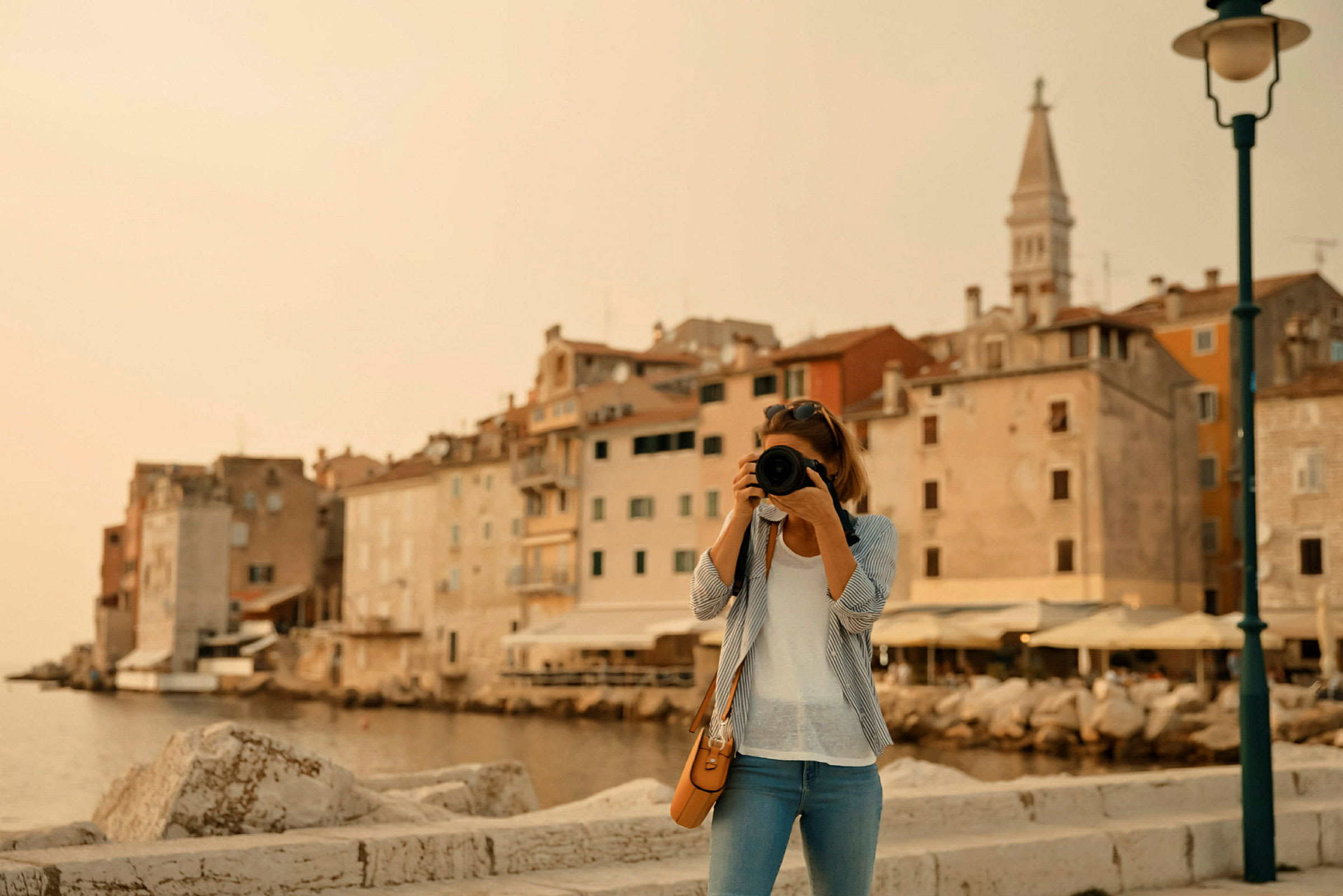 En person fotograferar en stad vid vattnet med en kamera. (AI-genererad text)