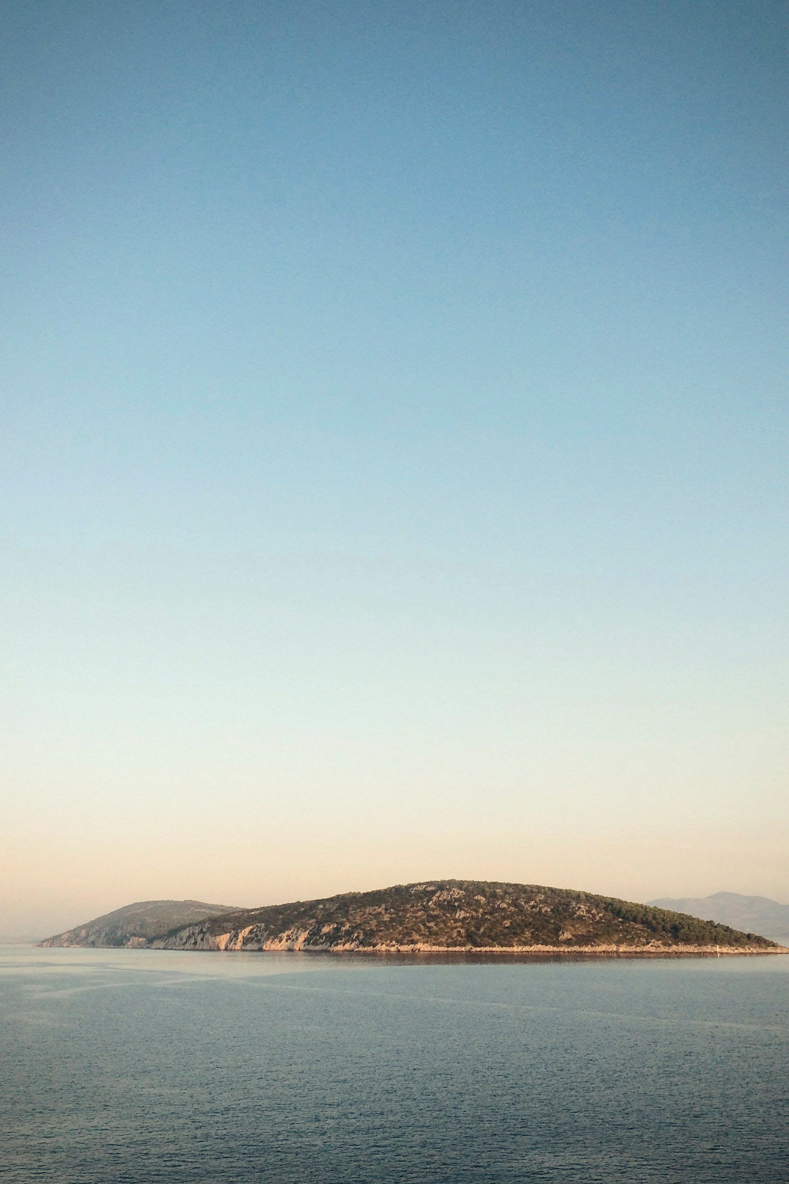 En liten ö i havet under en klar himmel. (AI-genererad text)