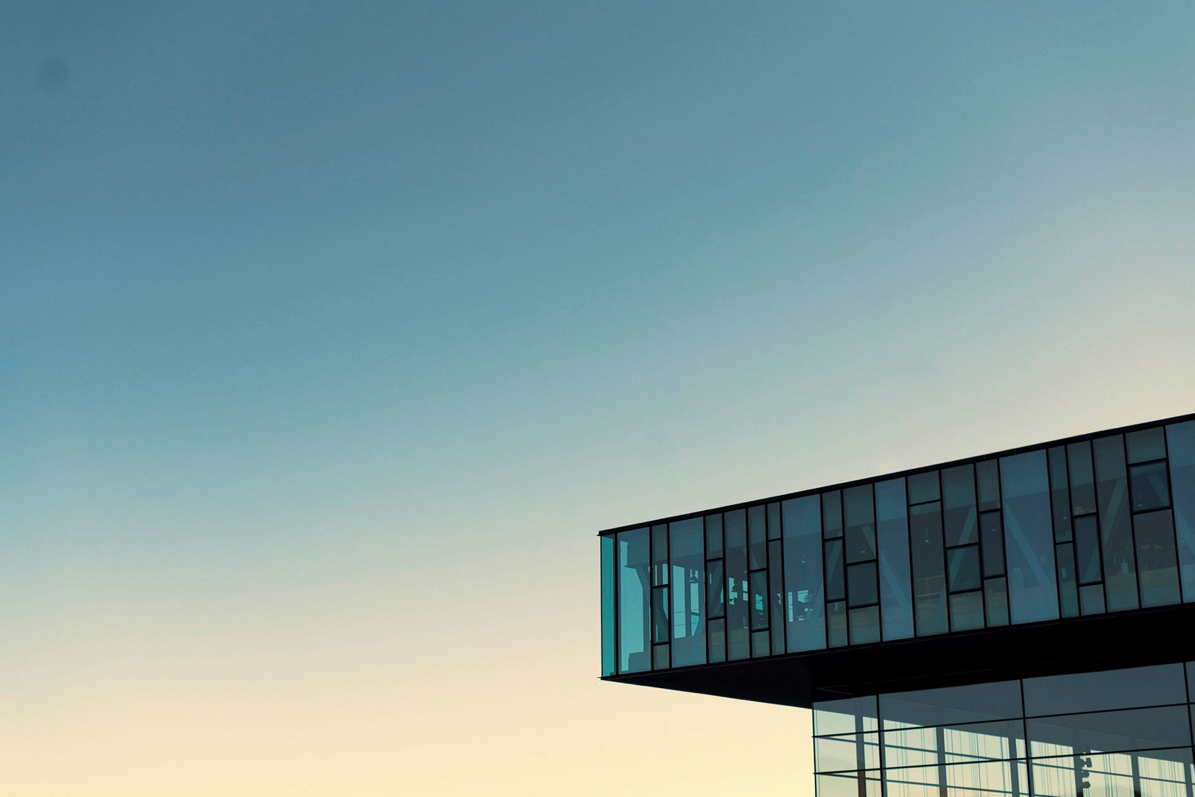 Modern byggnad med glasfönster mot en ljus himmel. (AI-genererad text)