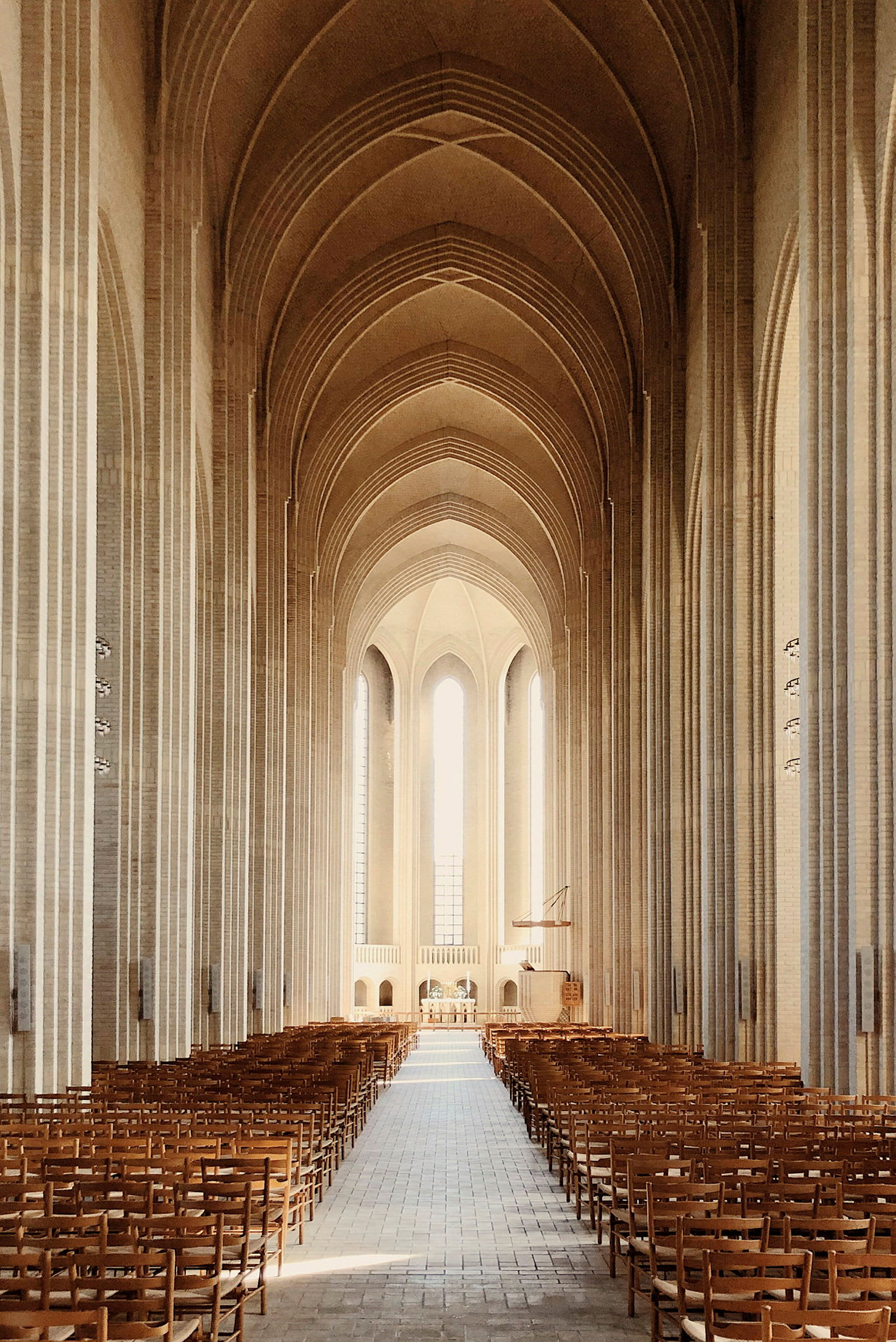 Interiören av en stor kyrka med höga valv och många trästolar. (AI-genererad text)
