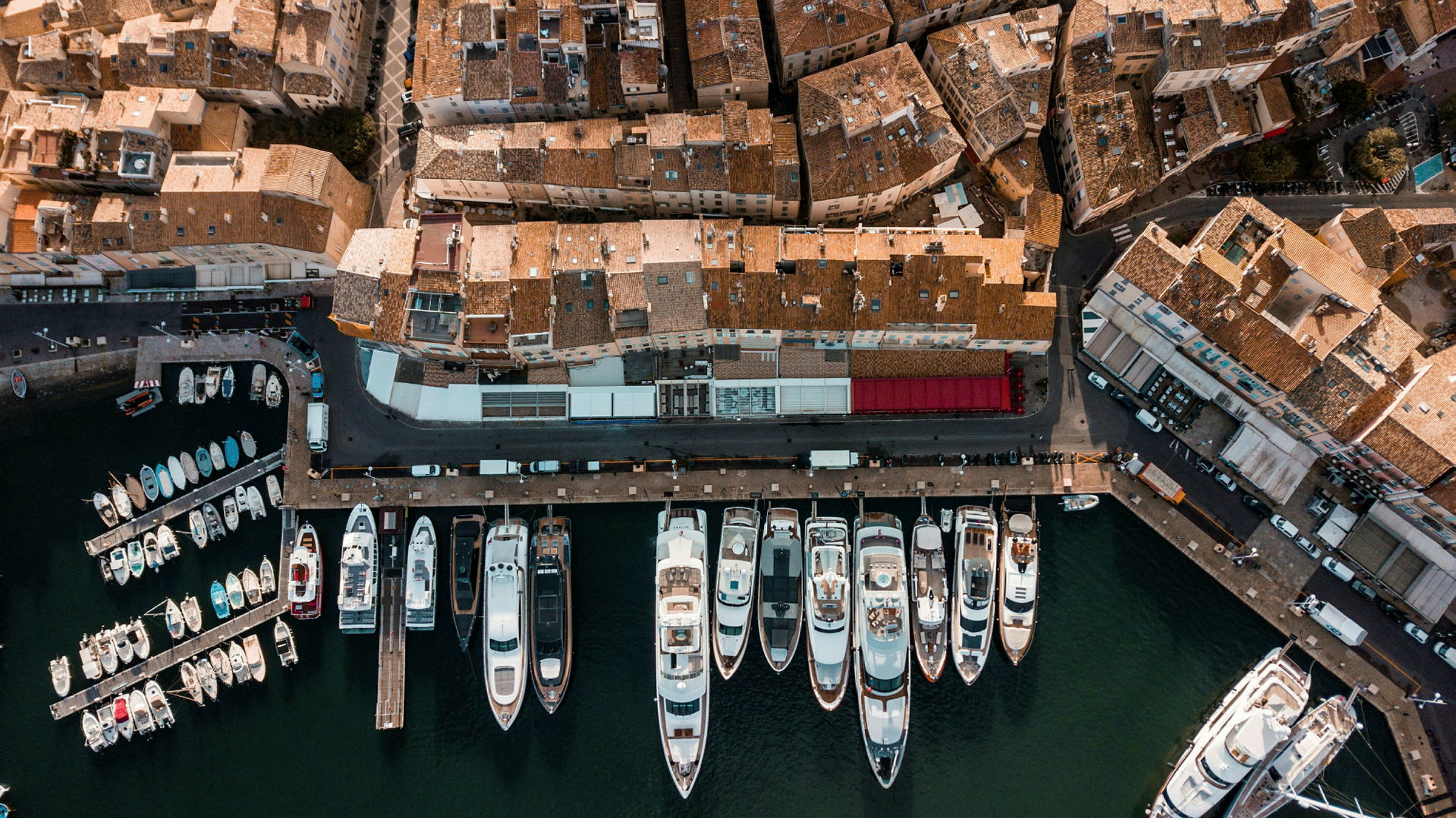 Flygfoto av en hamn med flera båtar och omgivande byggnader. (AI-genererad text)