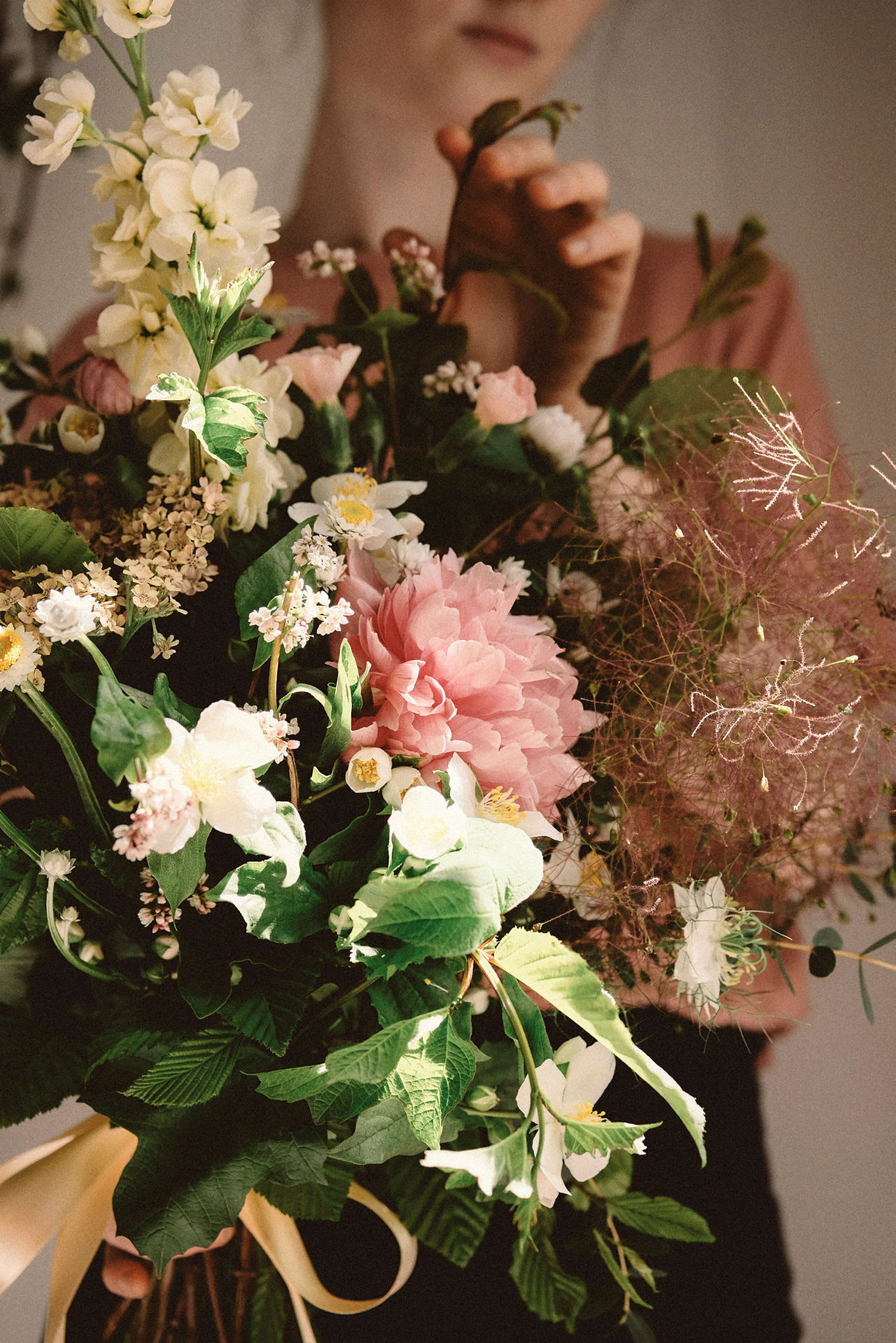 En kvinna håller en bukett med blommor i olika färger. (AI-genererad text)