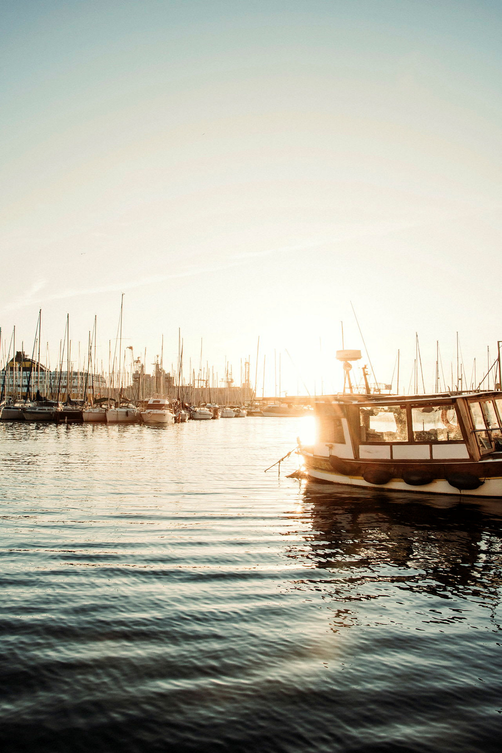 En solbelyst hamn med båtar och reflektion i vattnet. (AI-genererad text)