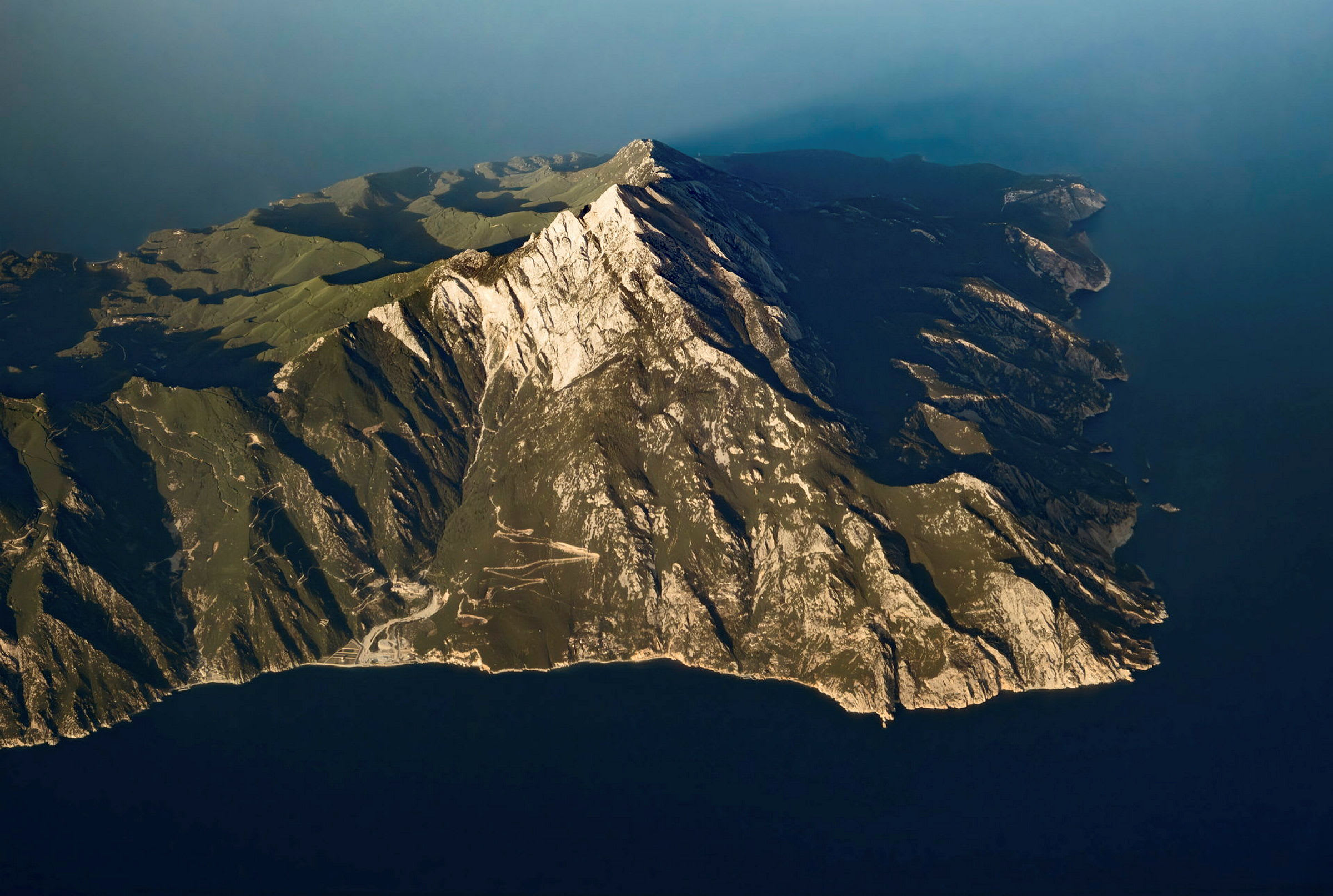 Flygfoto av ett bergsområde som sträcker sig ut i havet. (AI-genererad text)