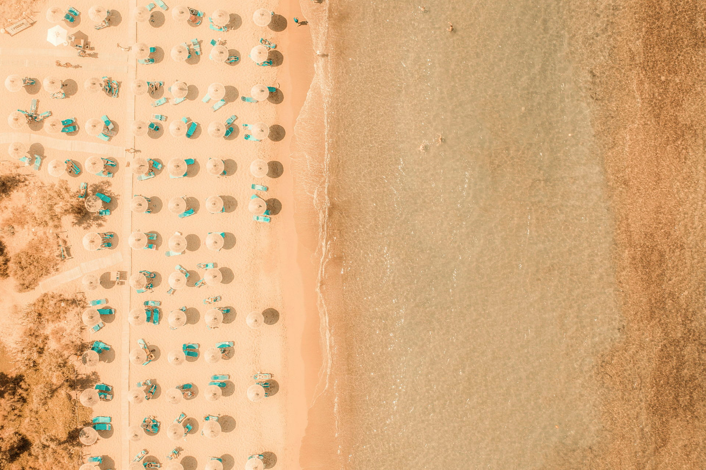 Strand med parasoller och solstolar, sett ovanifrån. (AI-genererad text)