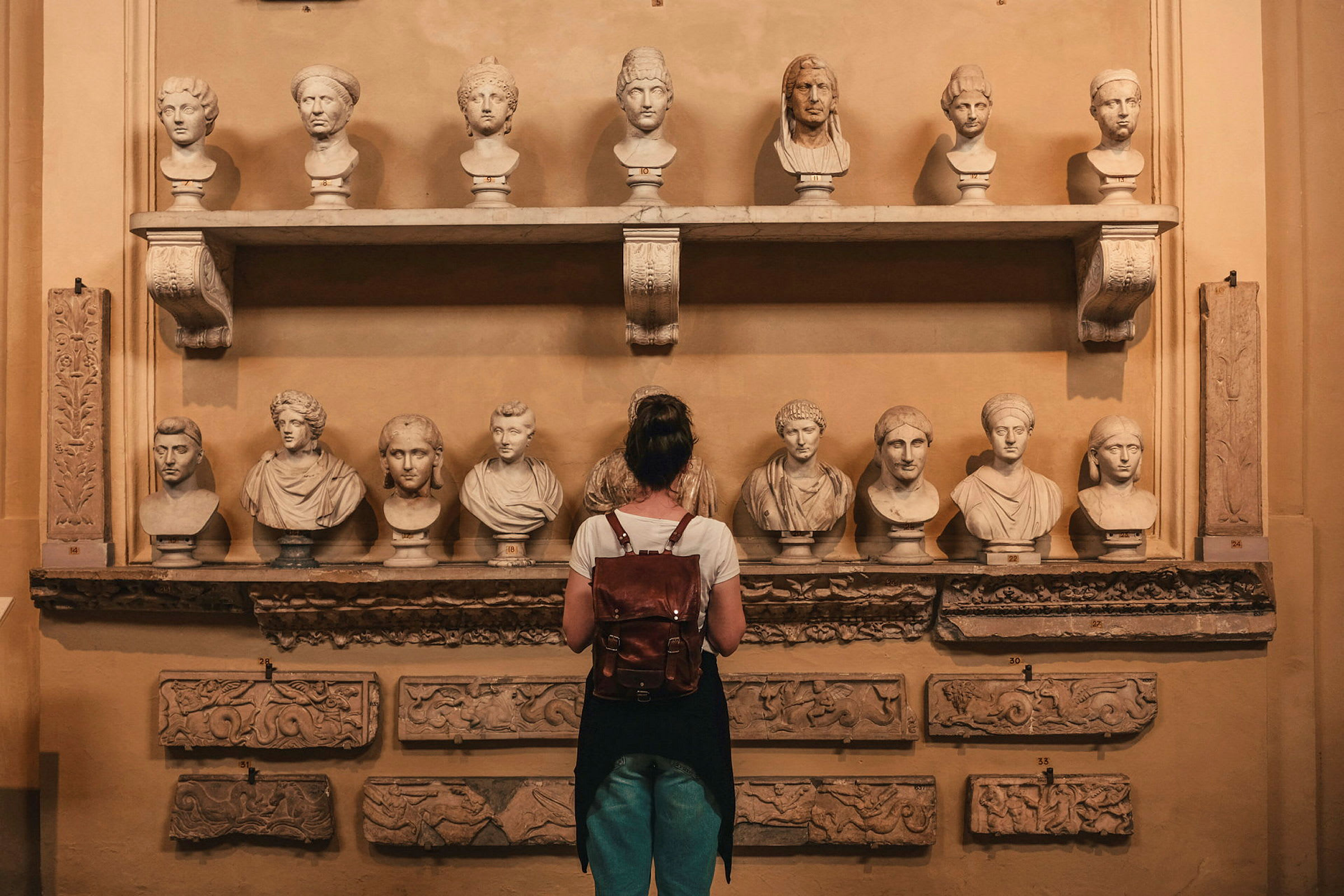 Person som betraktar statyer och reliefer i ett museum. (AI-genererad text)