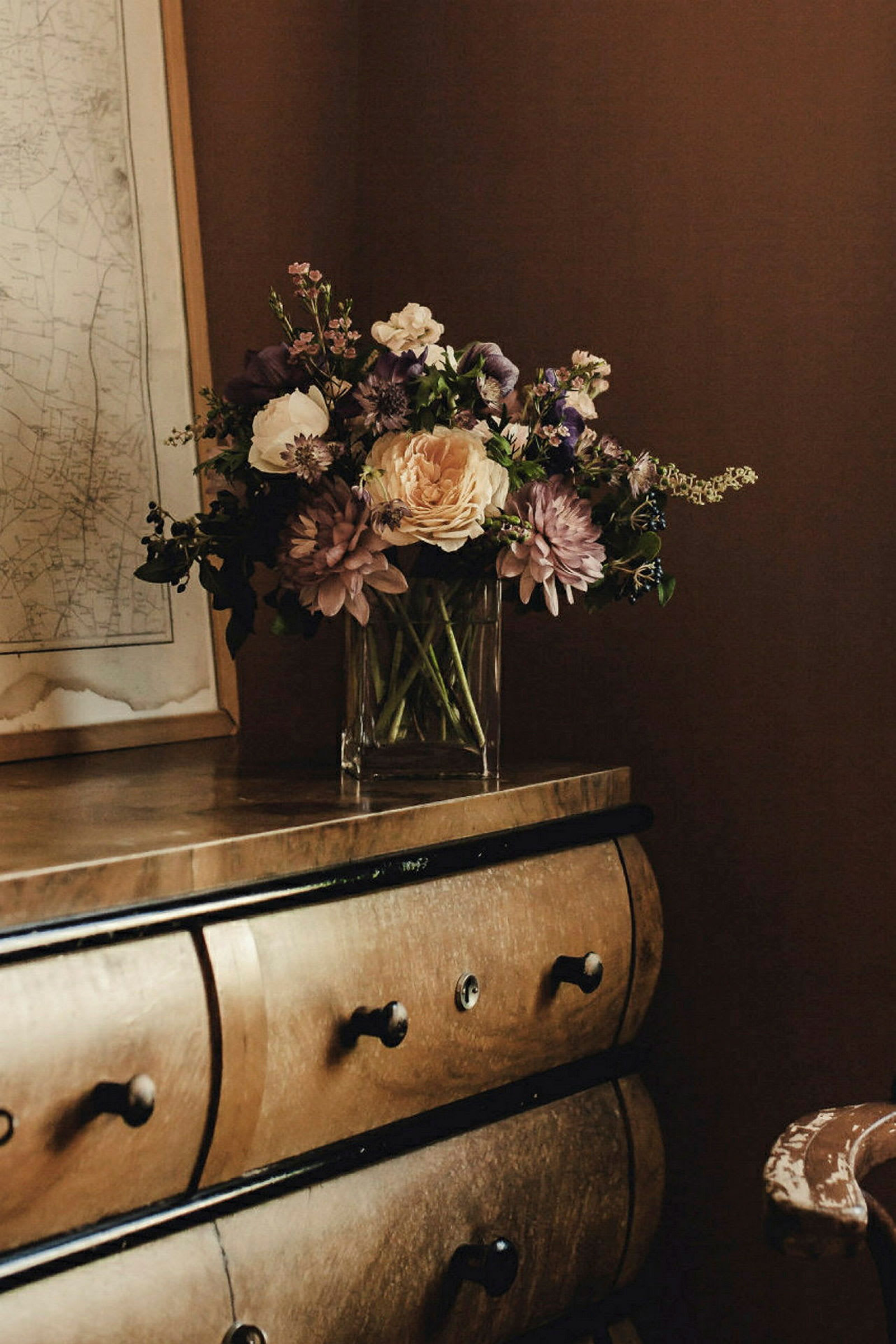 En elegant vas med blommor står på en träbyrå. (AI-genererad text)