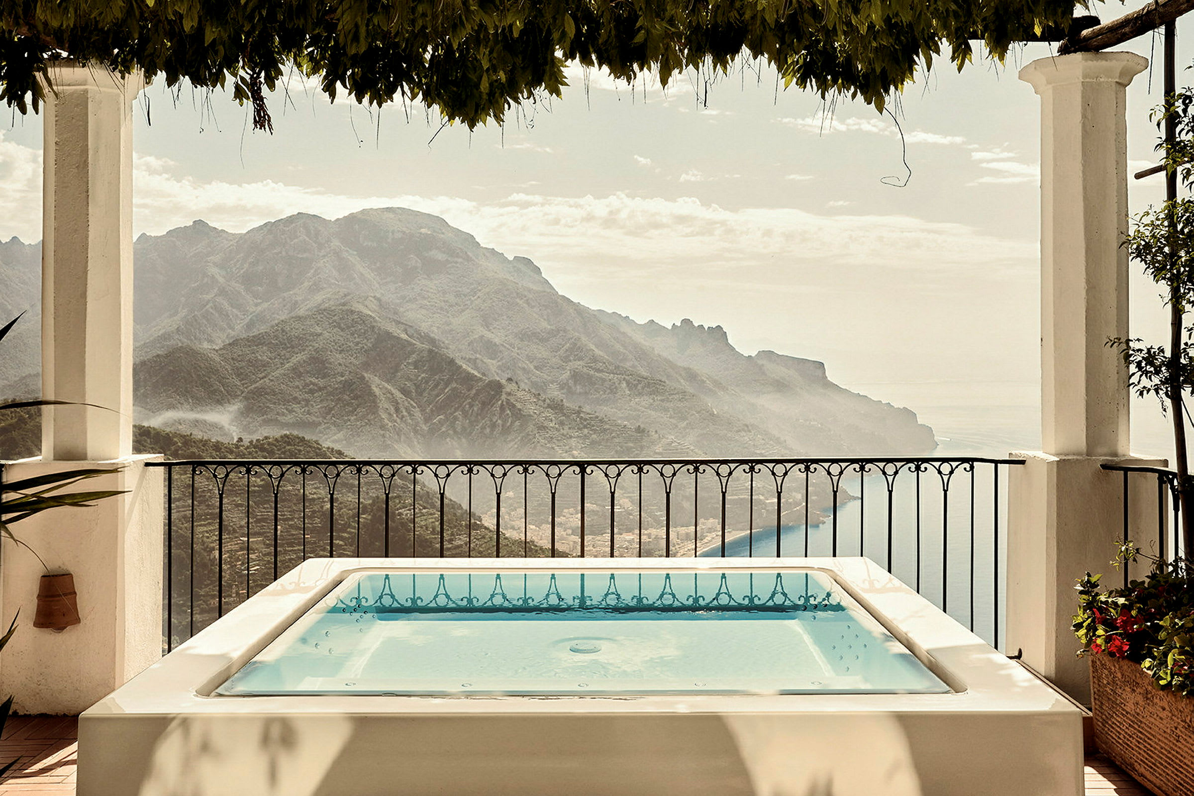 Terrass med jacuzzi och utsikt över berg och hav. (AI-genererad text)