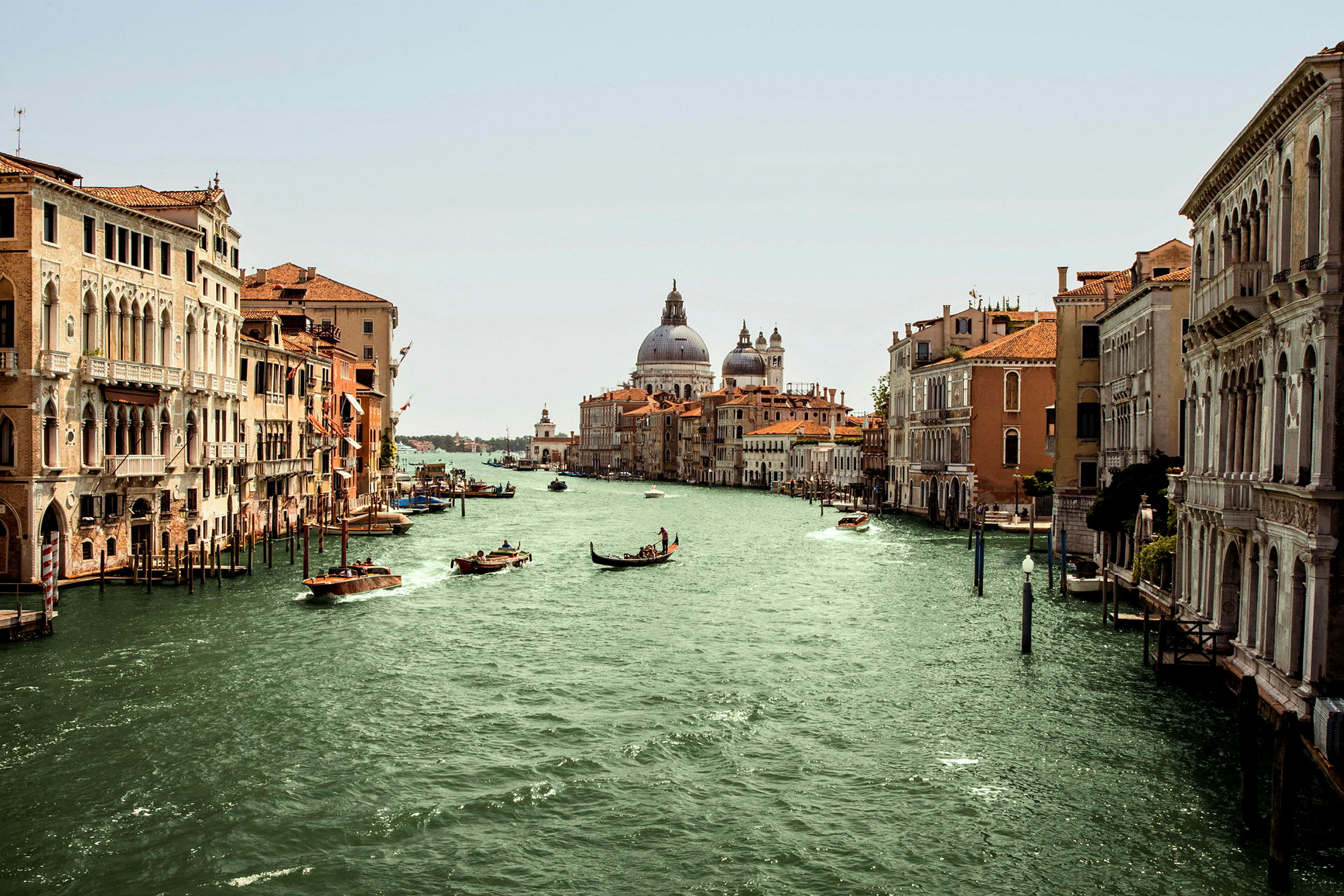 En kanal i Venedig omgiven av historiska byggnader med båtar och gondoler på vattnet. (AI-genererad text)