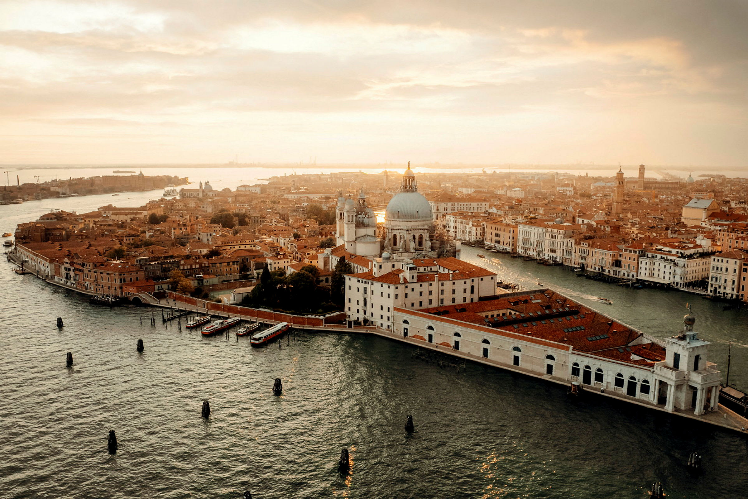 Flygvy över Venedig med kanaler, byggnader och en domkyrka vid solnedgång. (AI-genererad text)