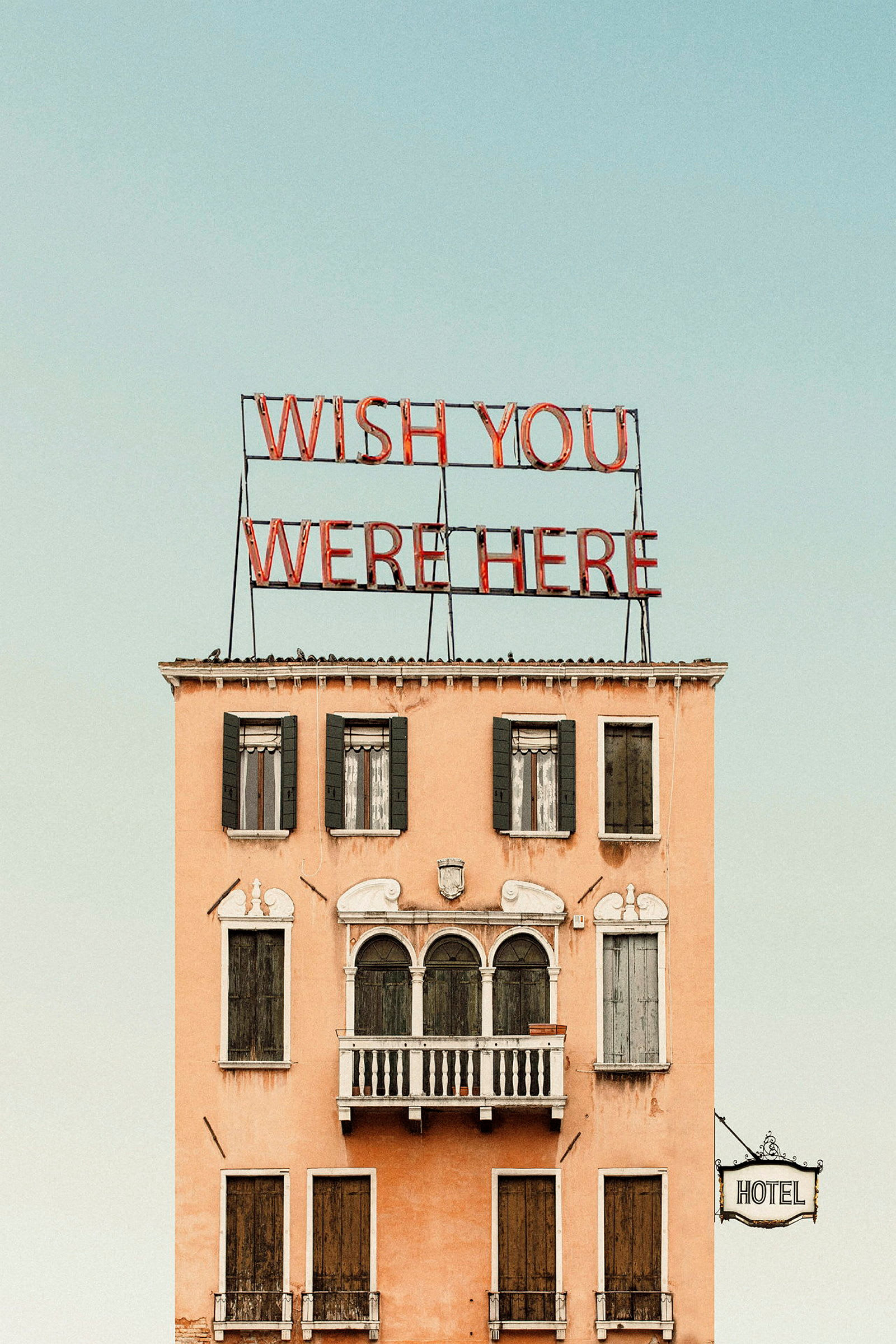 En byggnad med texten 'Wish you were here' på toppen och en hotellskylt på sidan. (AI-genererad text)
