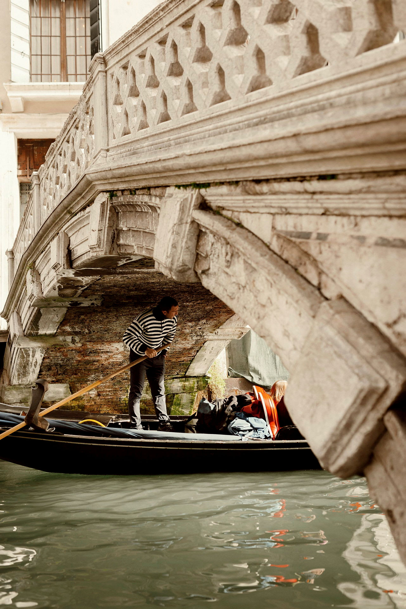 En gondol under en dekorerad stenbro i Venedig. (AI-genererad text)