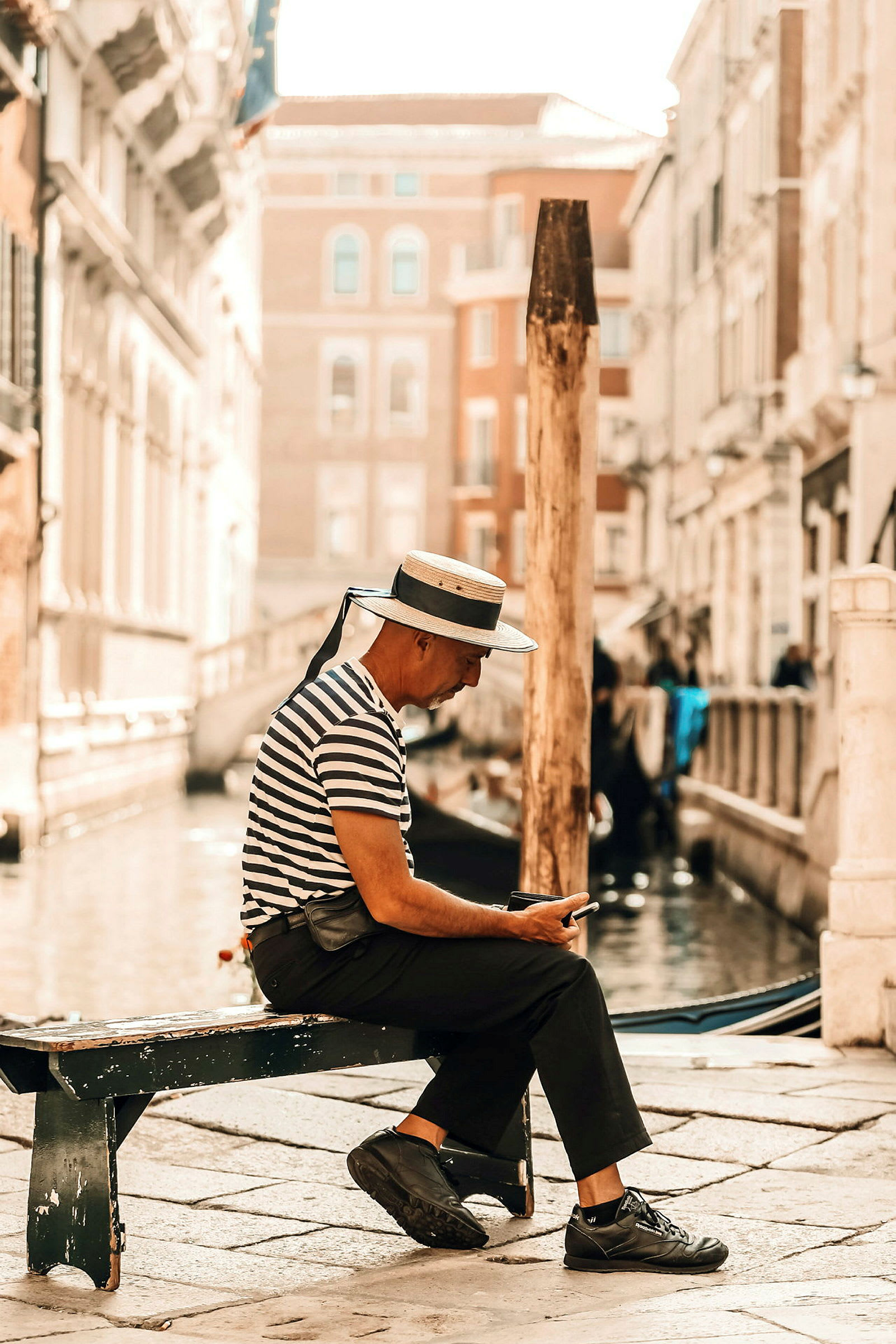 Person sitter på en bänk vid en venetiansk kanal. (AI-genererad text)
