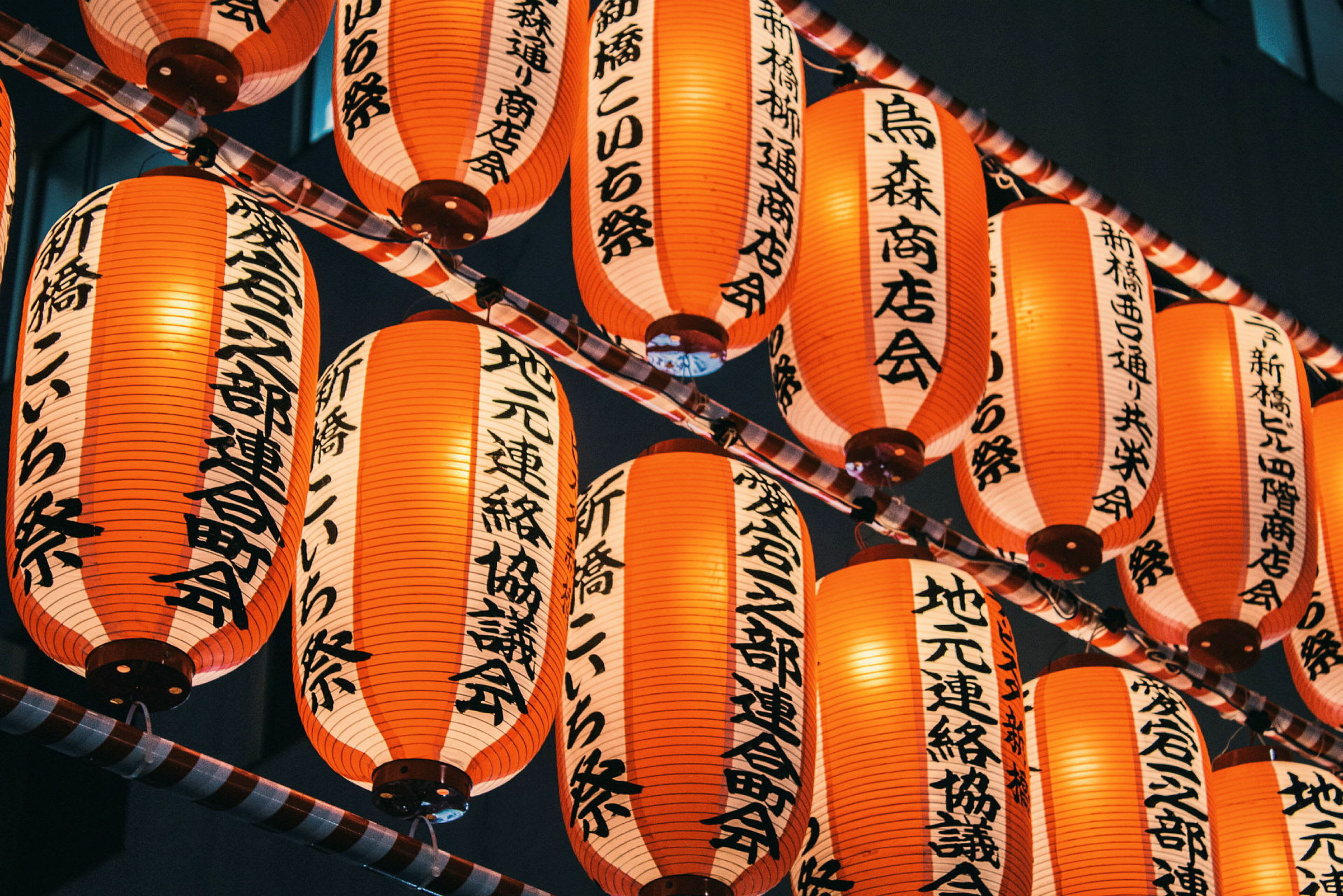 Flera röda japanska lyktor med svart text hängande i rader. (AI-genererad text)