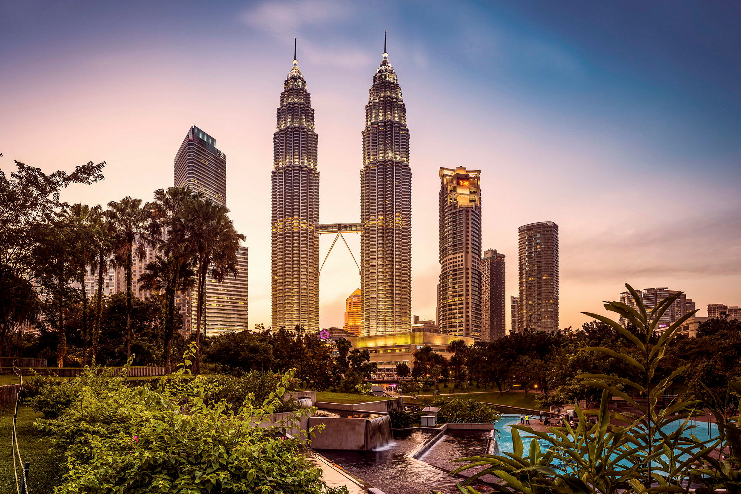 Bild av Petronas Twin Towers i Kuala Lumpur vid solnedgången från en park. (AI-genererad text)