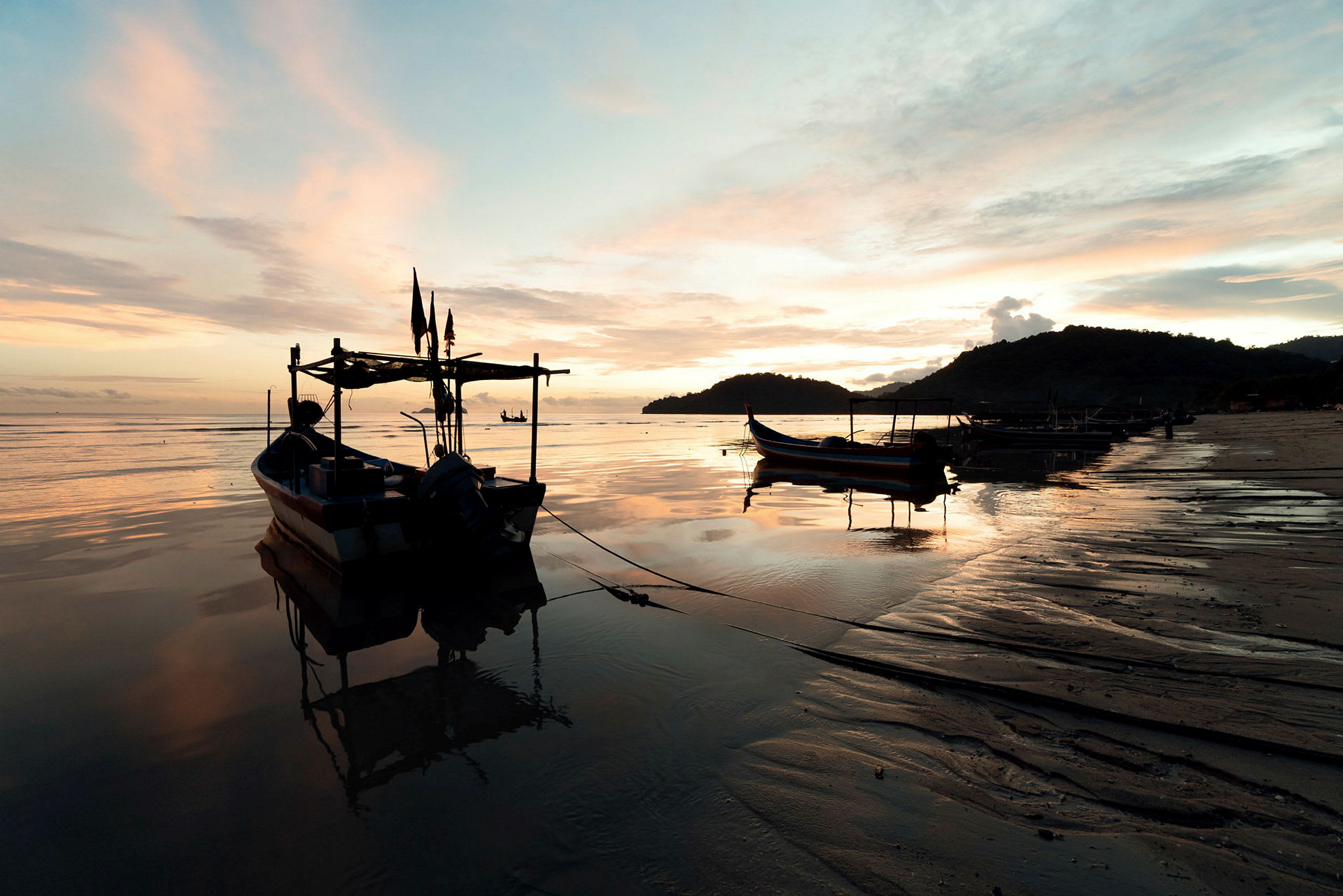 Fiskebåtar vid en lugn strand i solnedgången. (AI-genererad text)