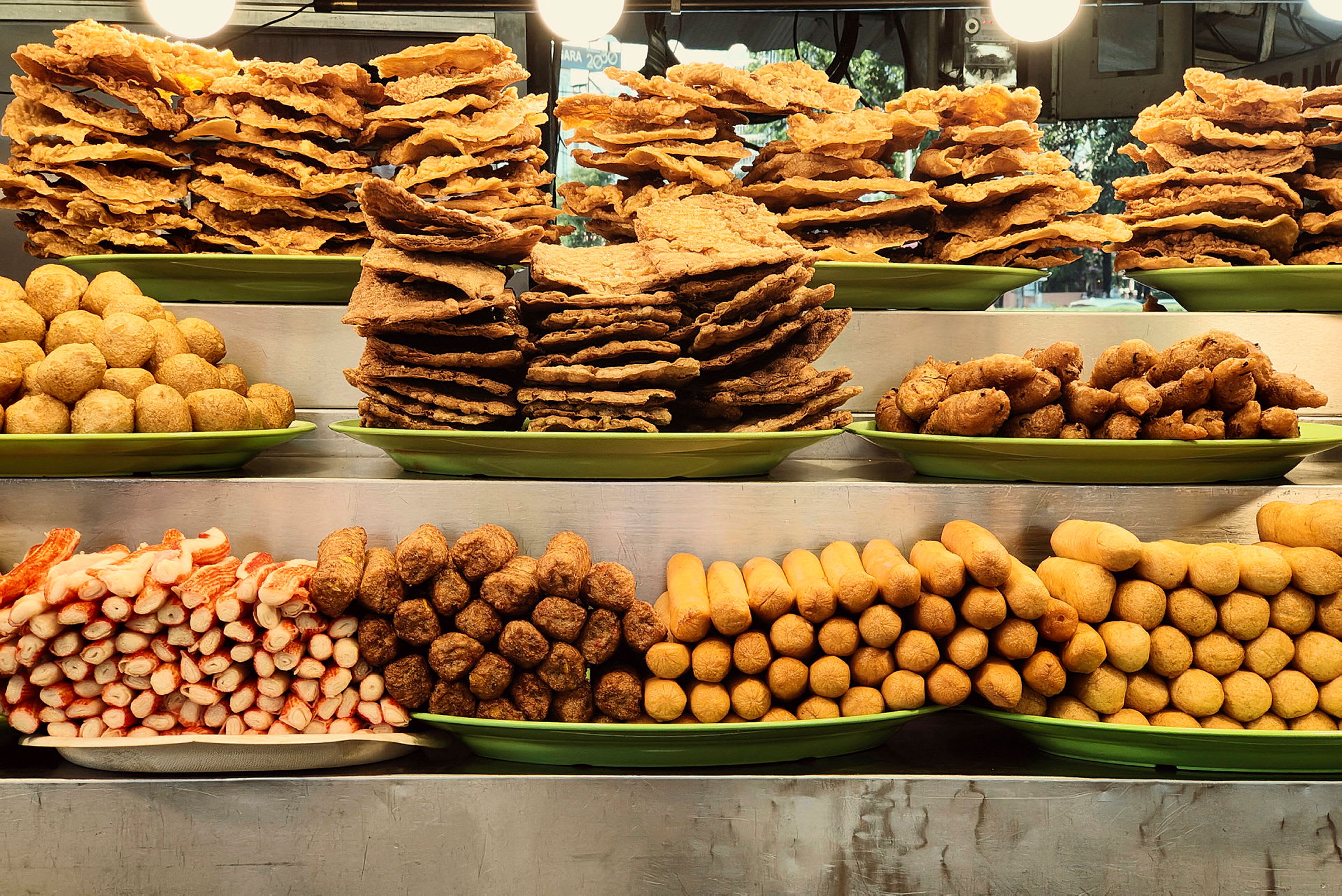 Olika sorters friterad mat och snacks upplagda i högar på gröna fat. (AI-genererad text)
