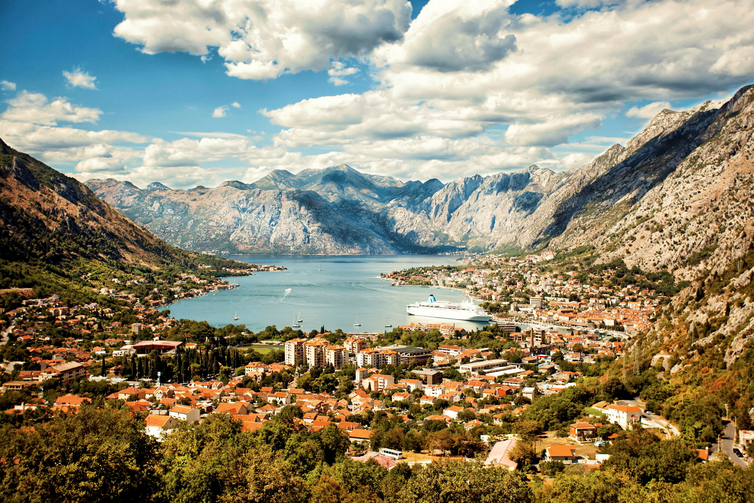 Vy över en stad vid en vik med berg i bakgrunden. (AI-genererad text)