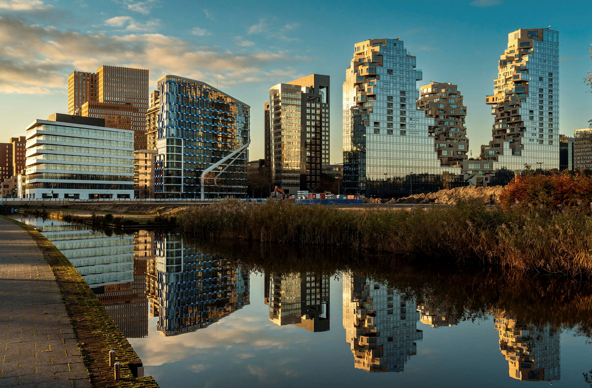 Flera moderna byggnader vid en vattenyta som reflekterar dem. (AI-genererad text)