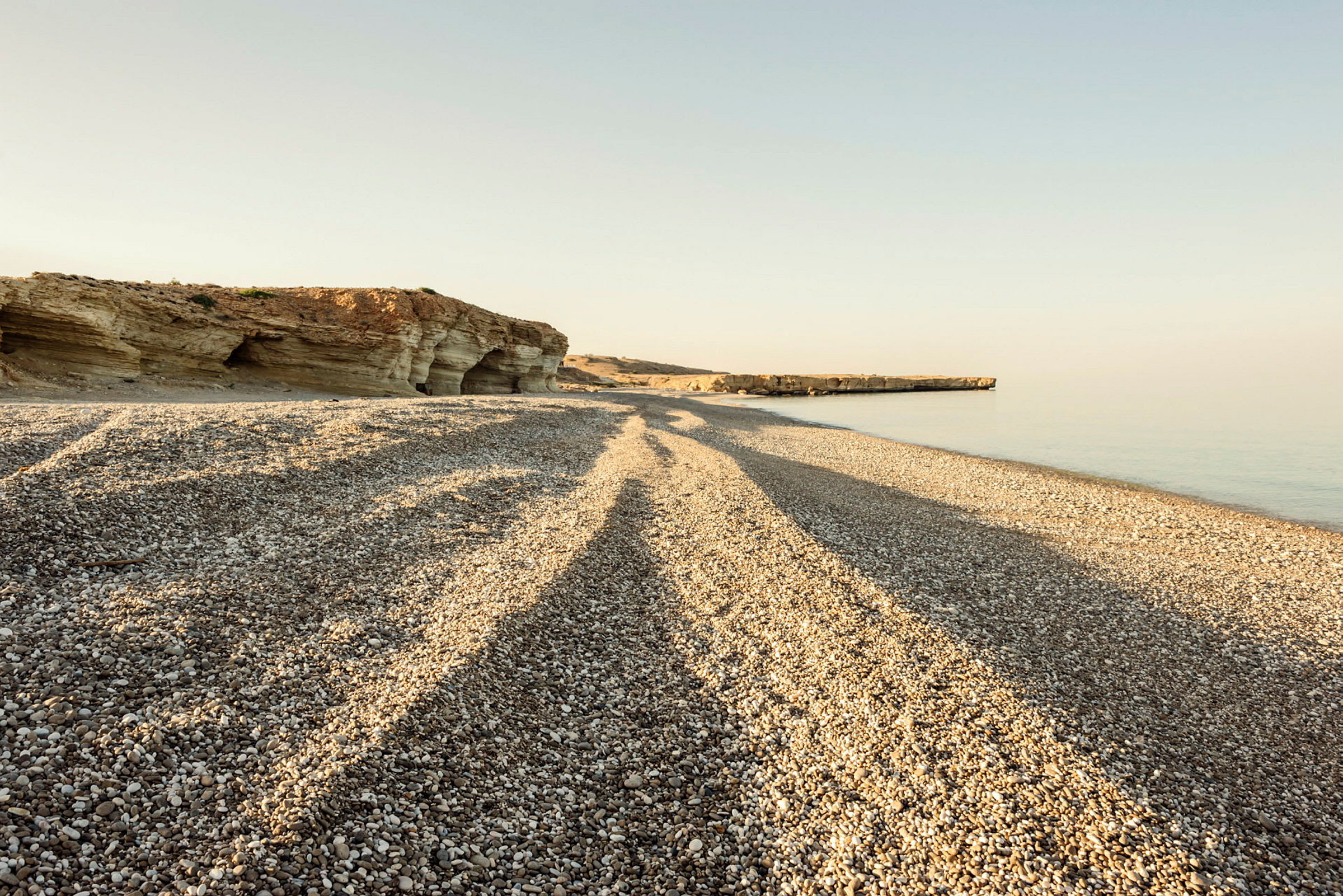 En strand med småsten och klippor i bakgrunden. (AI-genererad text)