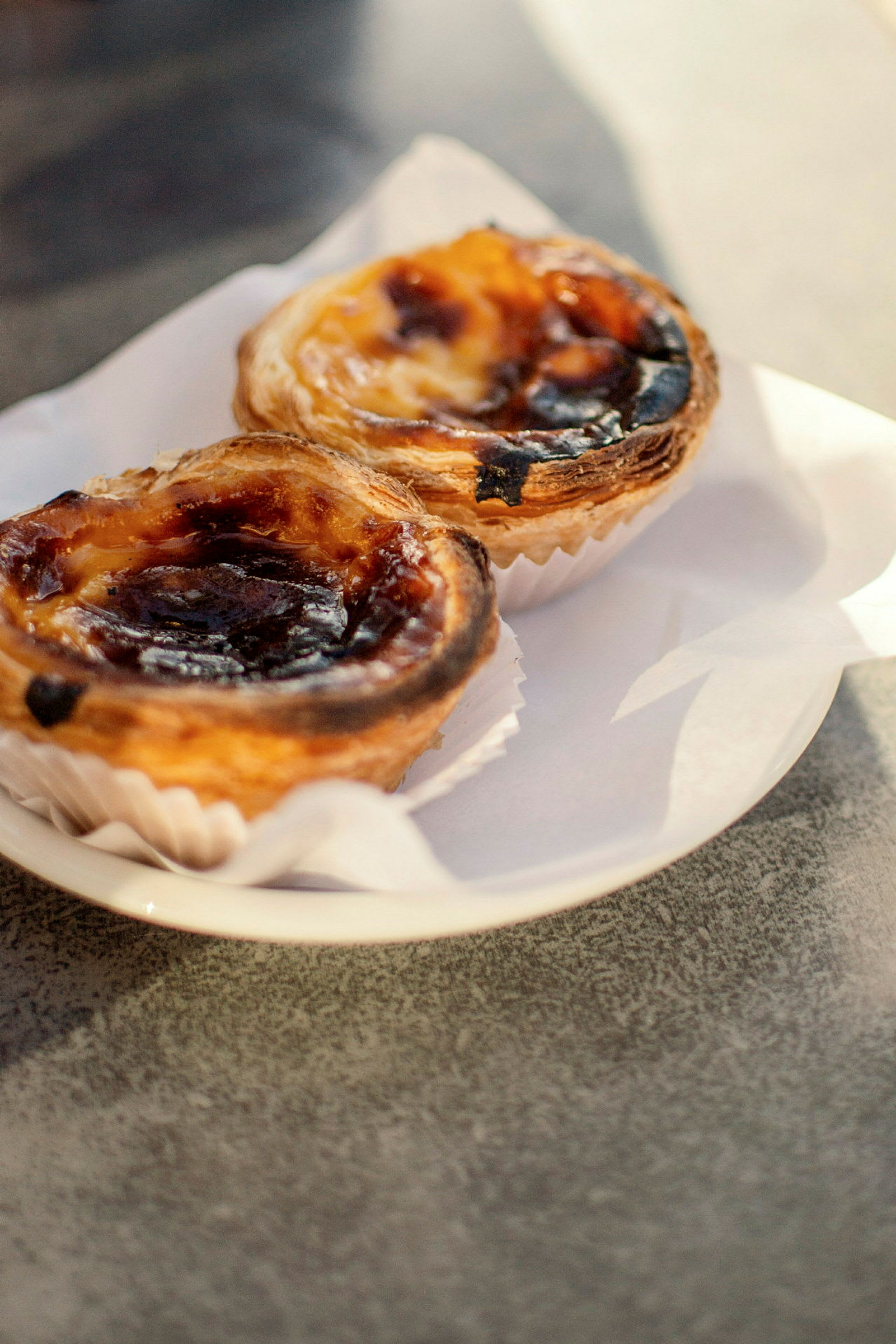 Två pastéis de nata på en tallrik. (AI-genererad text)