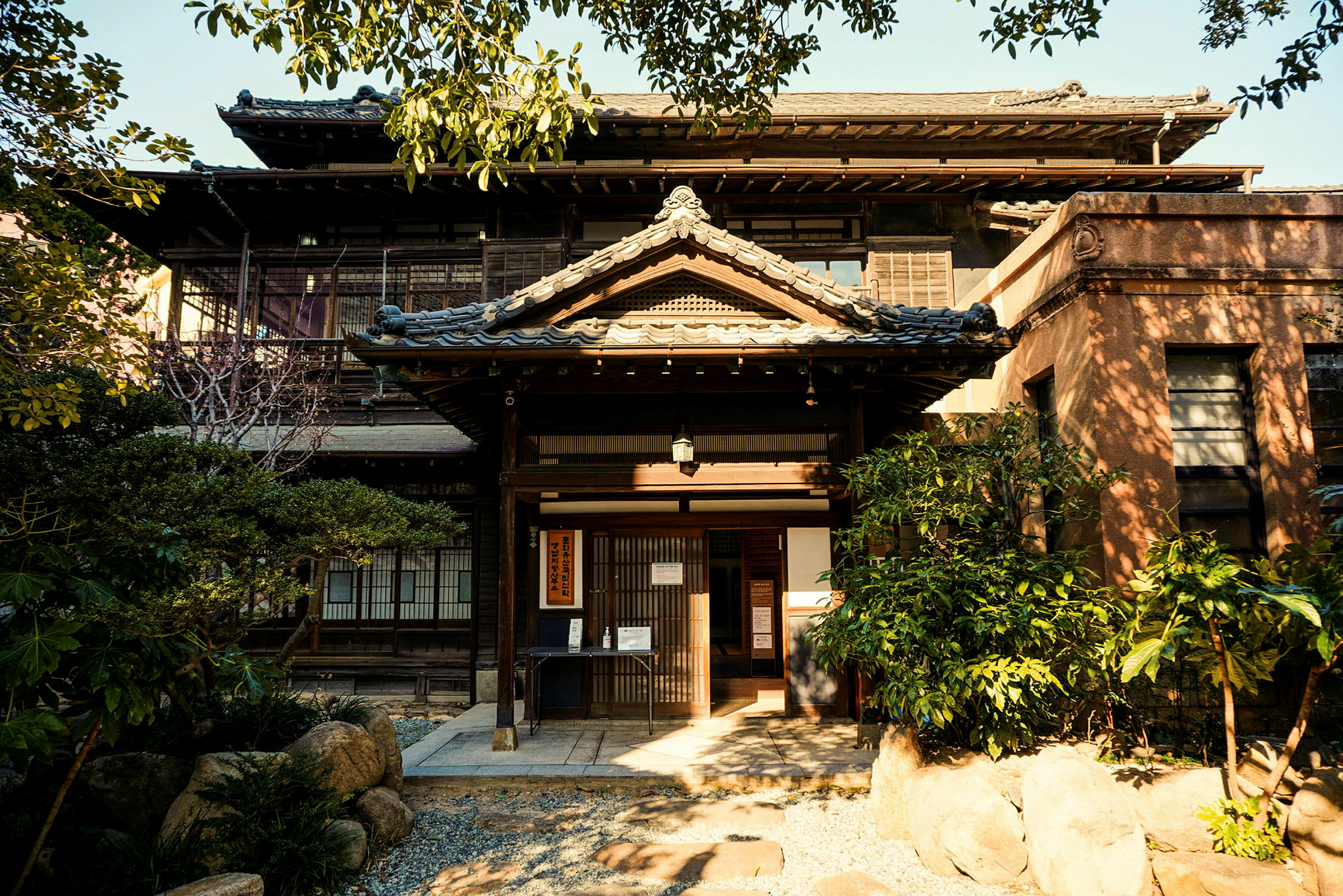 En traditionell japansk byggnad med en ingång och omgivande trädgård. (AI-genererad text)