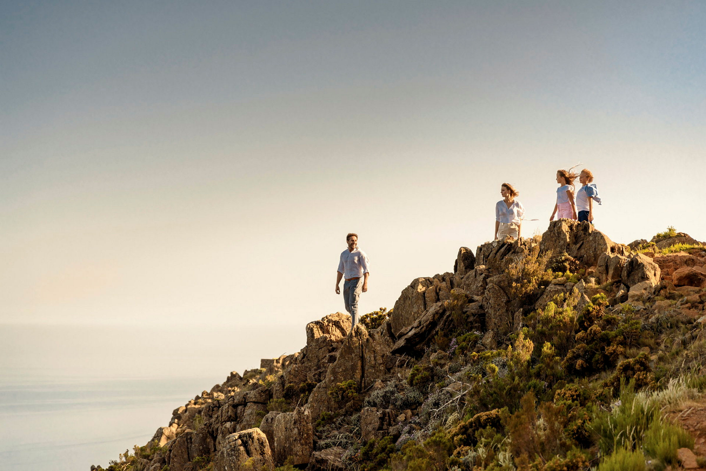 En grupp människor som går på en bergstopp med utsikt över havet. (AI-genererad text)