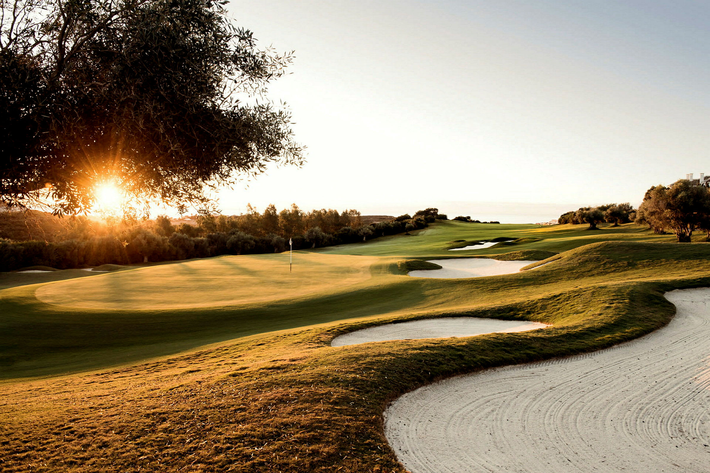 En golfbana vid solnedgång med sandbunkrar och grönska. (AI-genererad text)