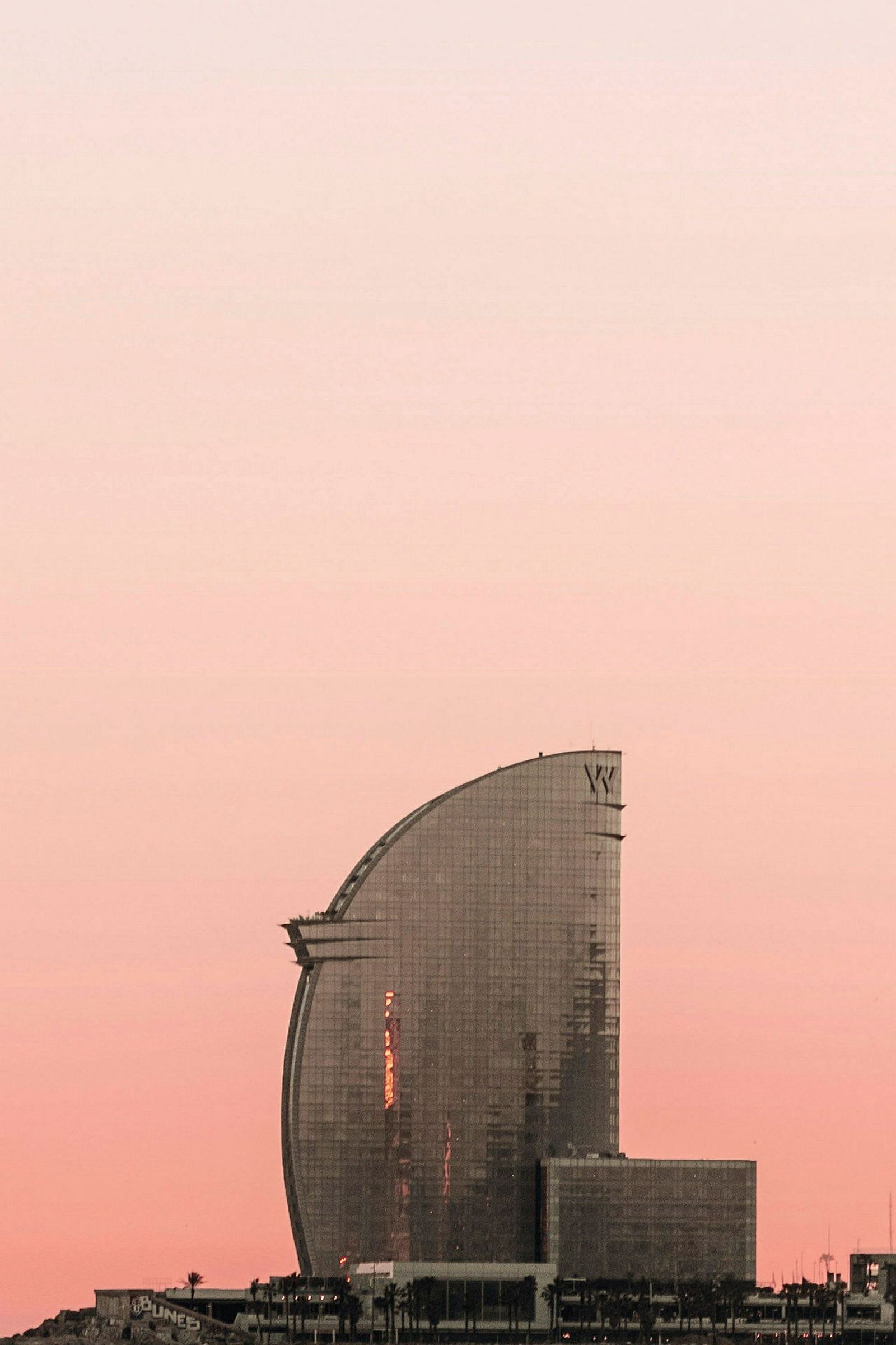 Höghus med glasyta framför en rosa himmel. (AI-genererad text)