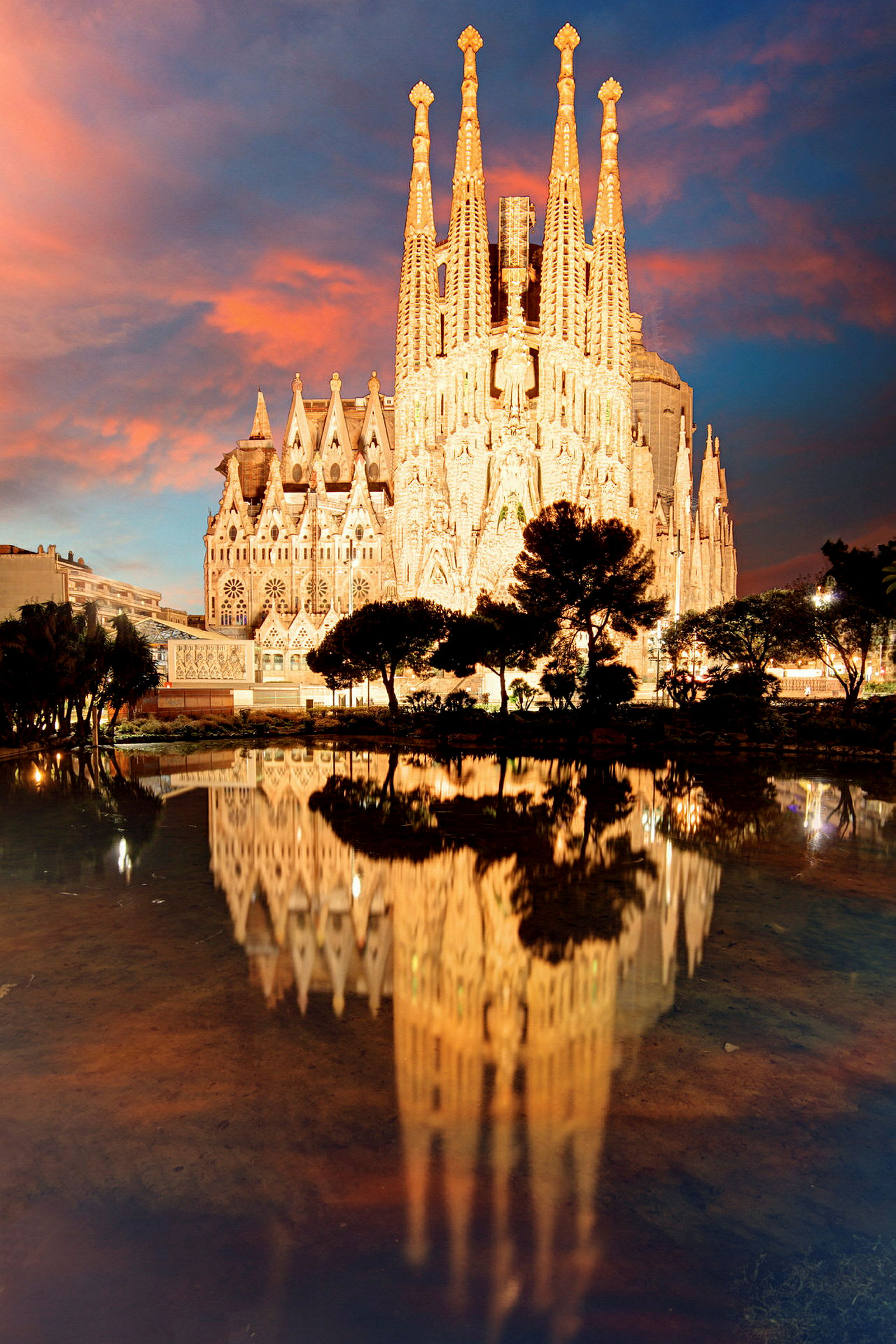 Sagrada Família i Barcelona i solnedgångsljus med en spegelbild i vatten. (AI-genererad text)