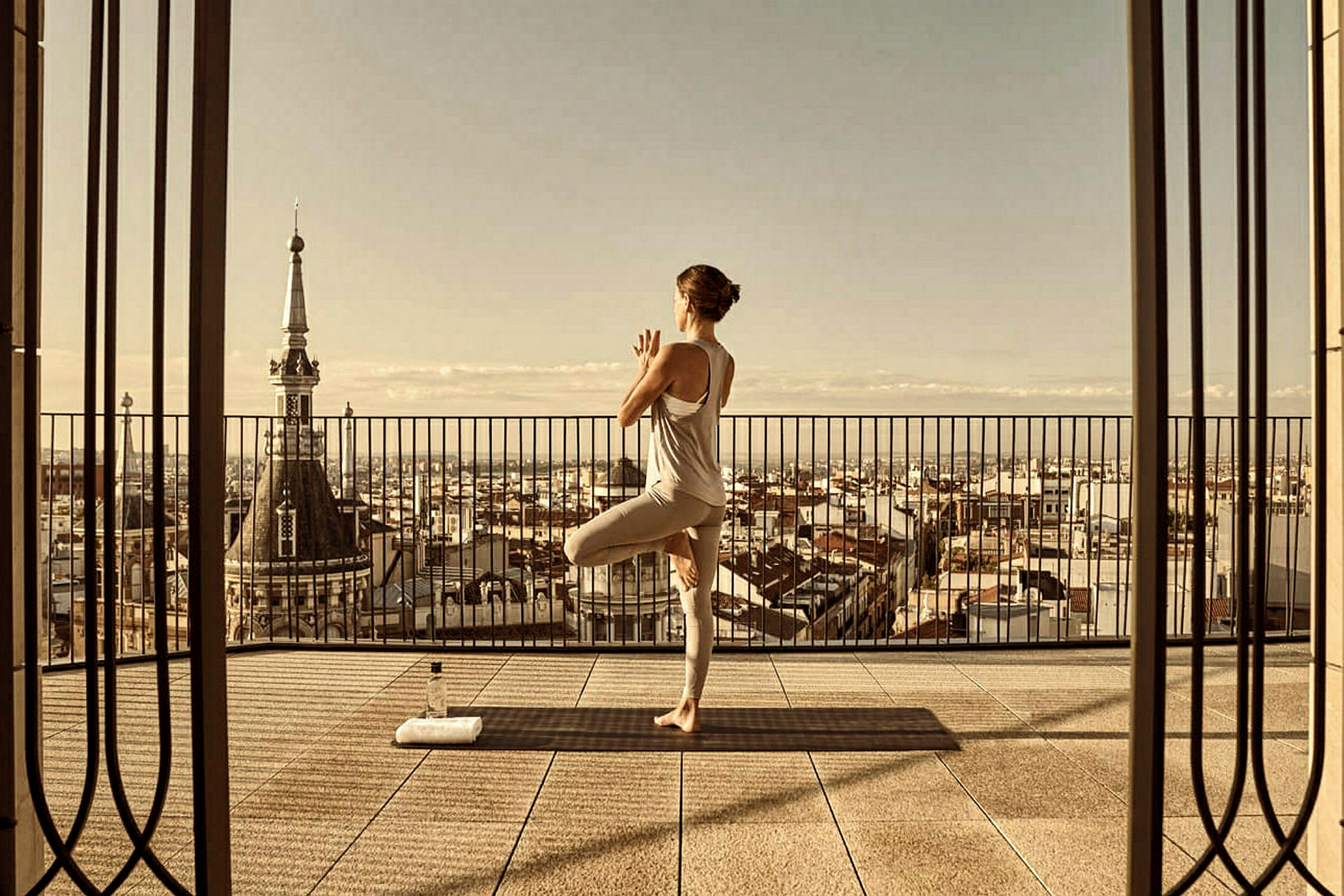 En person utför yoga på en terrass med utsikt över en stad. (AI-genererad text)