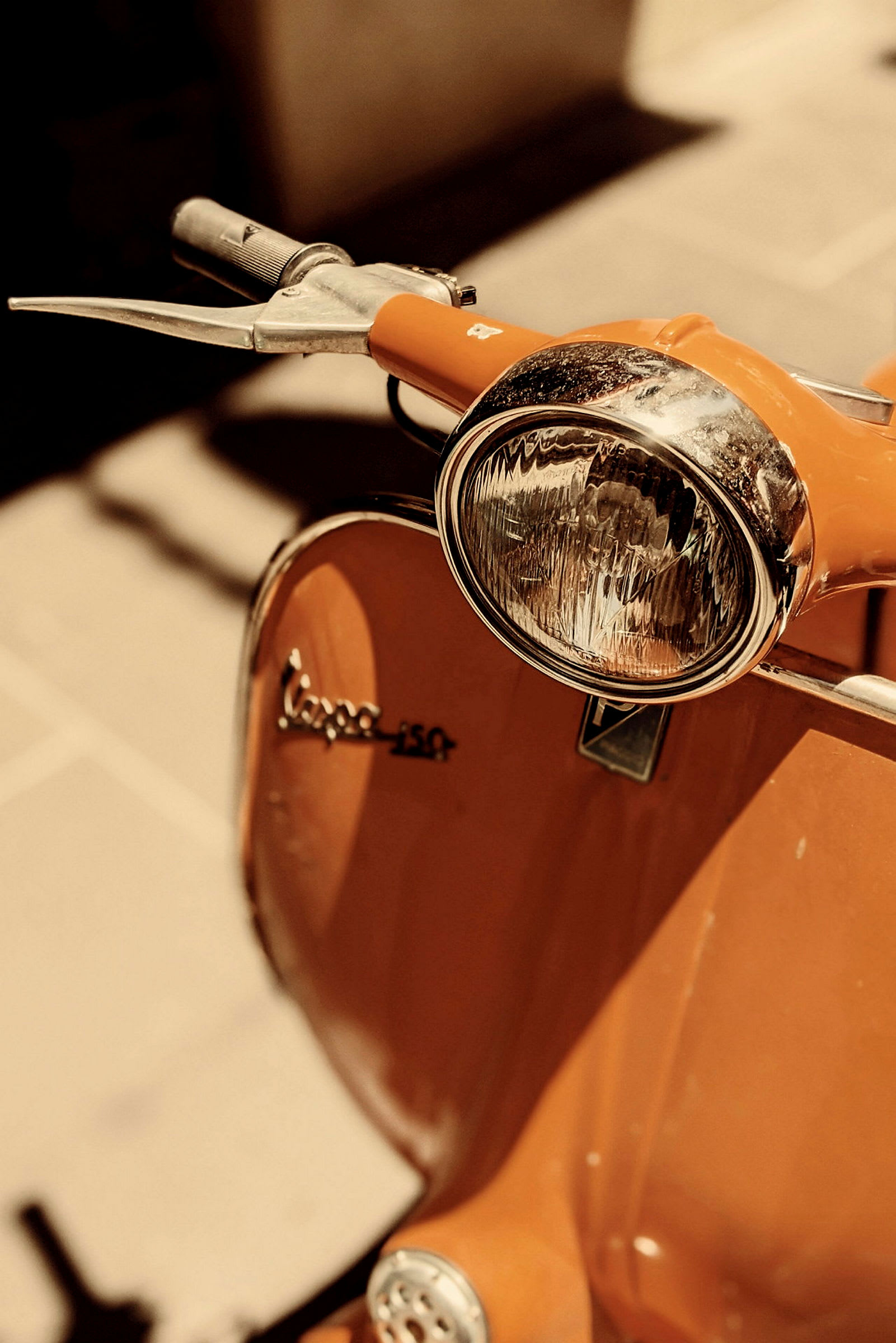 Orange Vespa scooter med framlykta i fokus. (AI-genererad text)