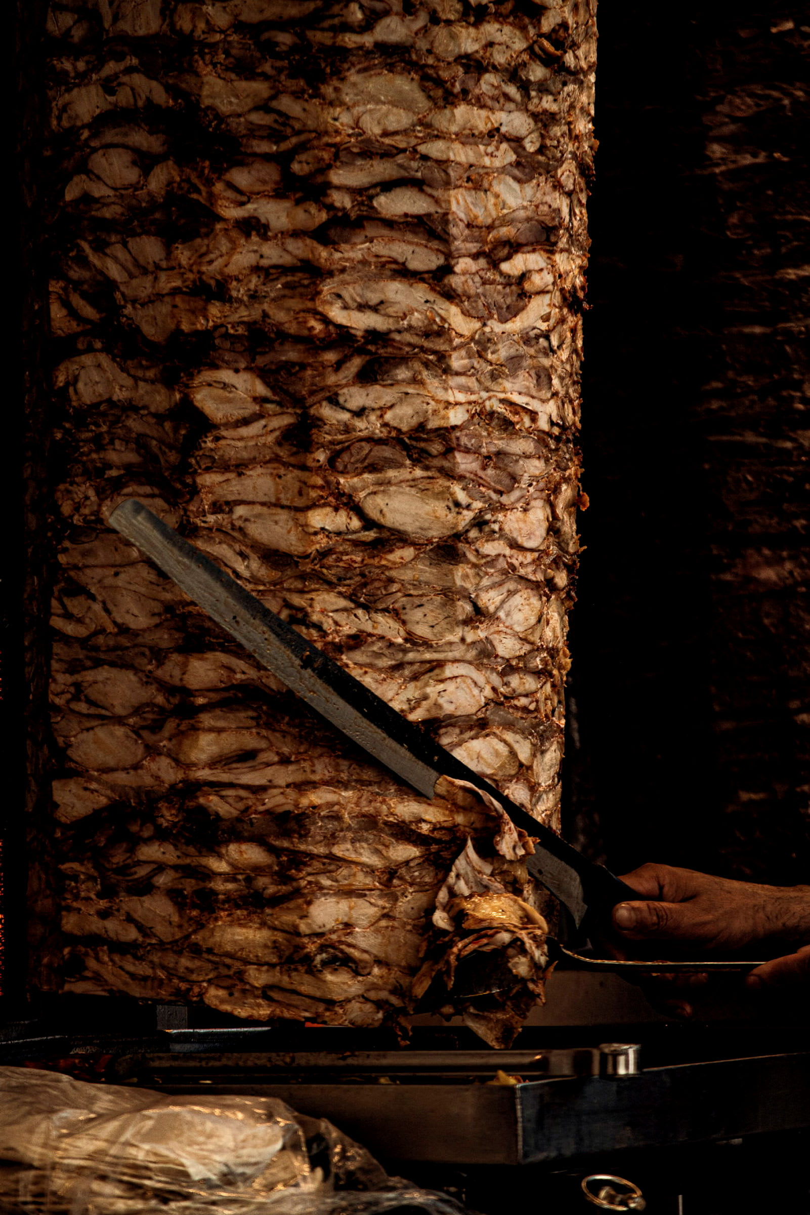 Stående köttspett med en hand som skär kött med kniv. (AI-genererad text)