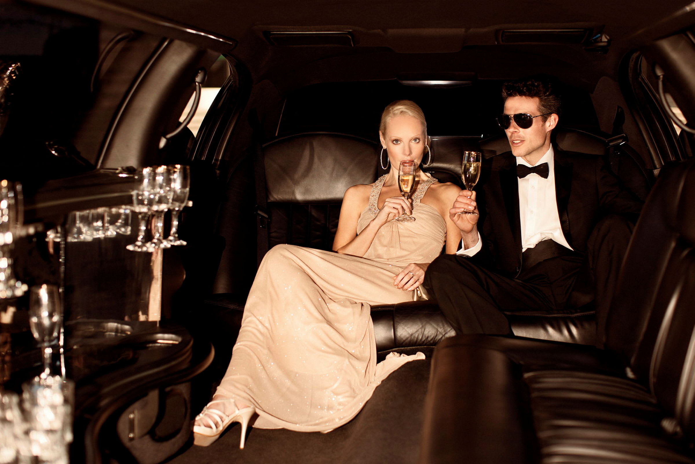 Två personer sitter i en lyxig limousine och håller glas. (AI-genererad text)
