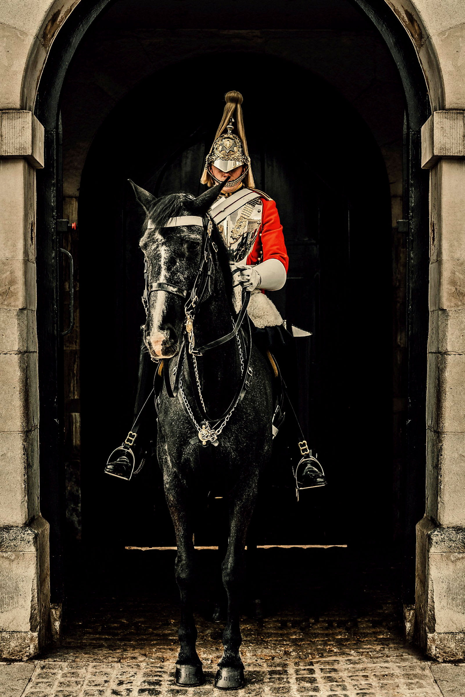 En soldat i röd uniform och traditionell hjälm sitter på en svart häst. (AI-genererad text)