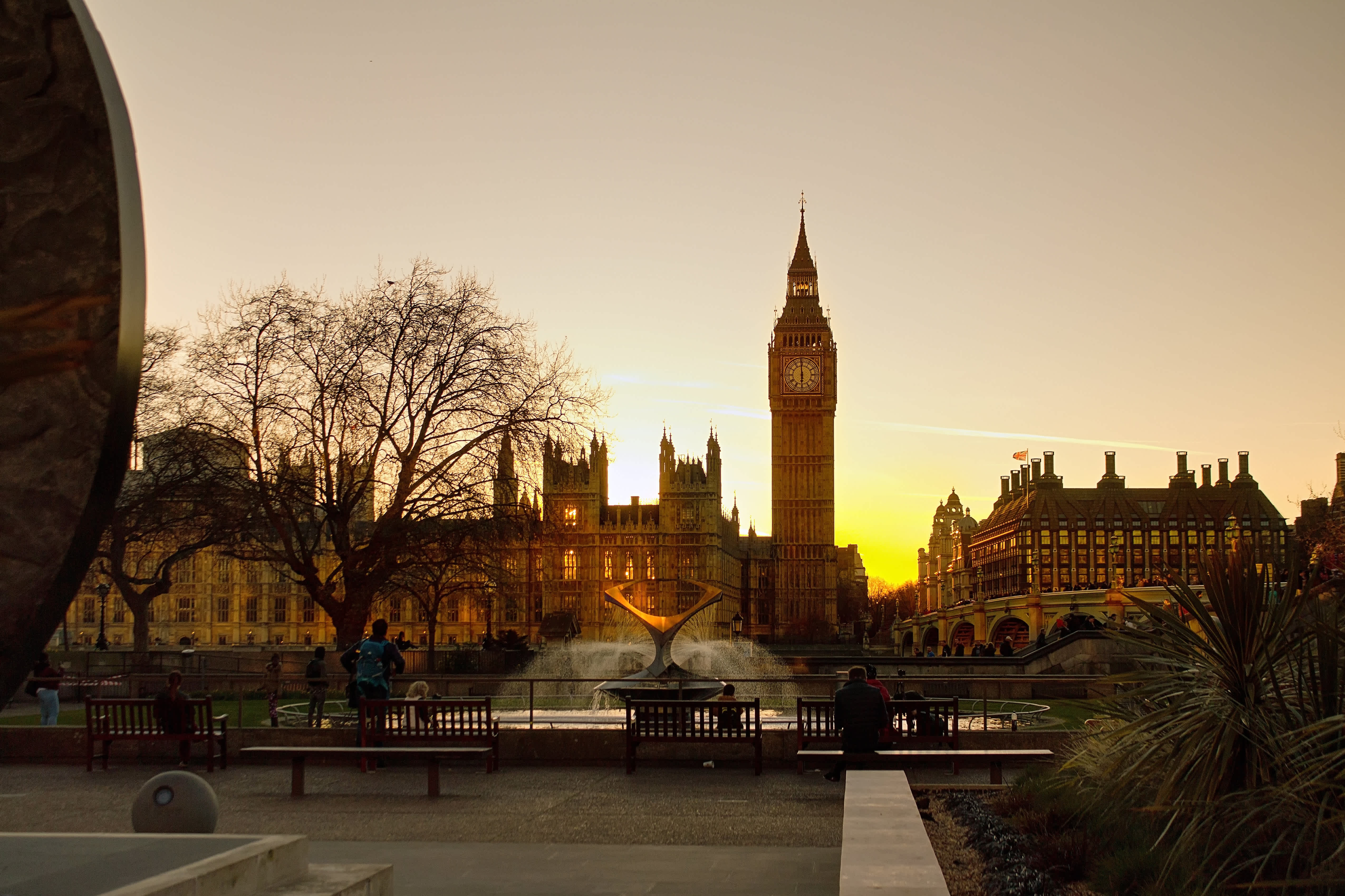 Vy över Big Ben och Westminster vid solnedgången, med en fontän i förgrunden. (AI-genererad text)
