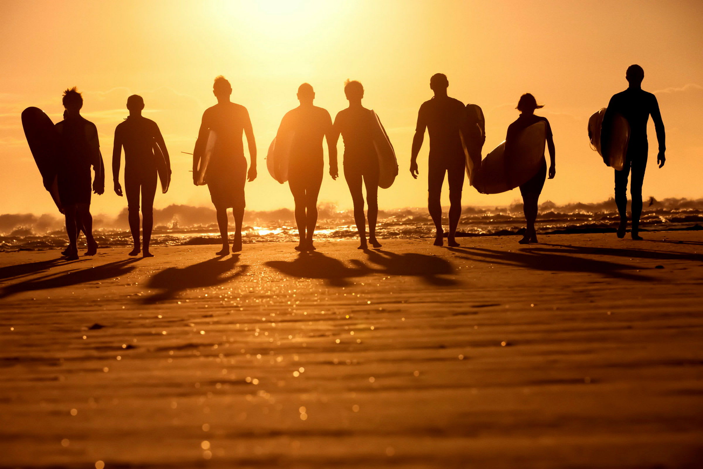 Surfare går på stranden vid solnedgången. (AI-genererad text)