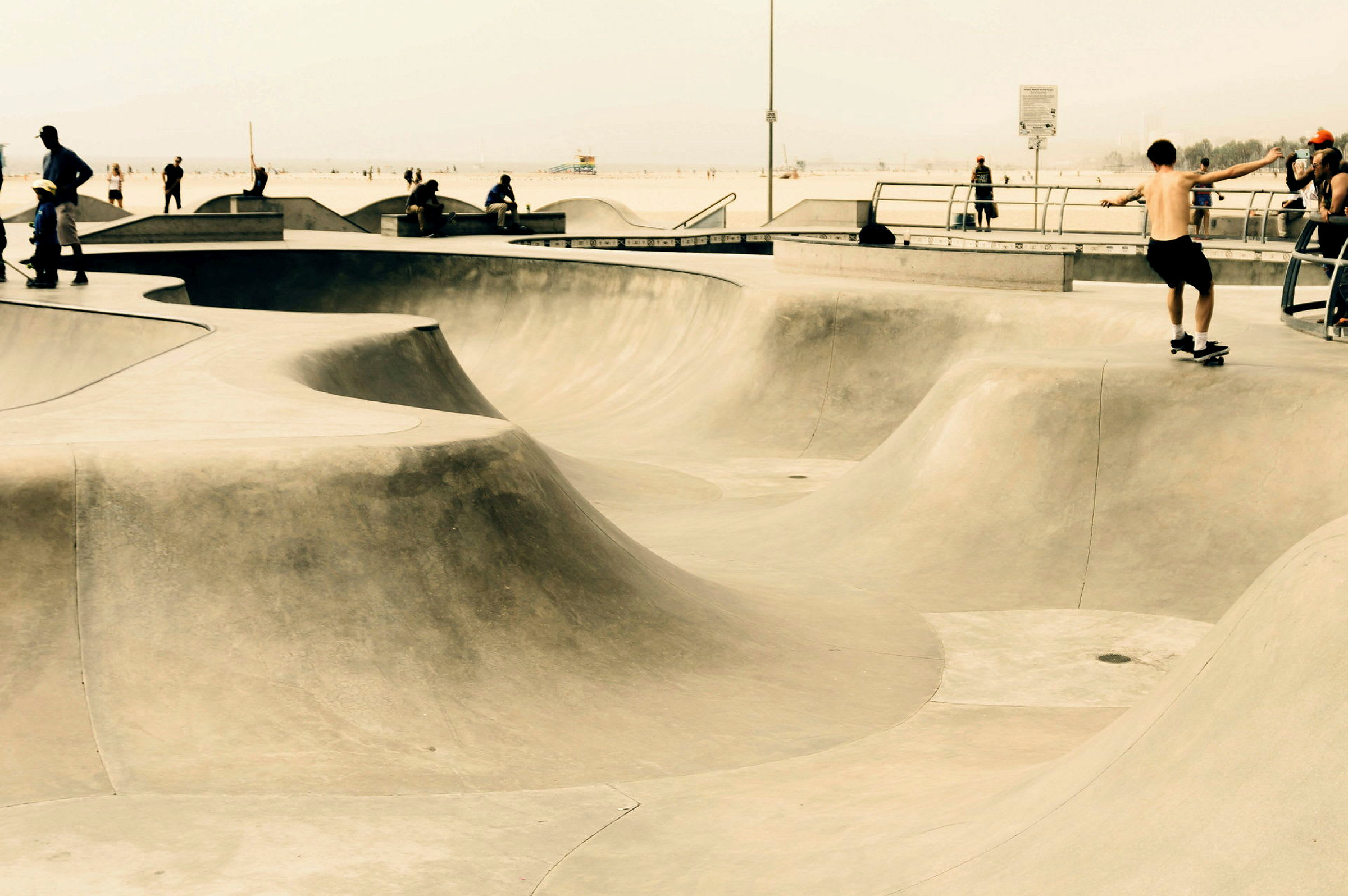 En skatepark med böljande betongramper används av personer för att åka skateboard. (AI-genererad text)