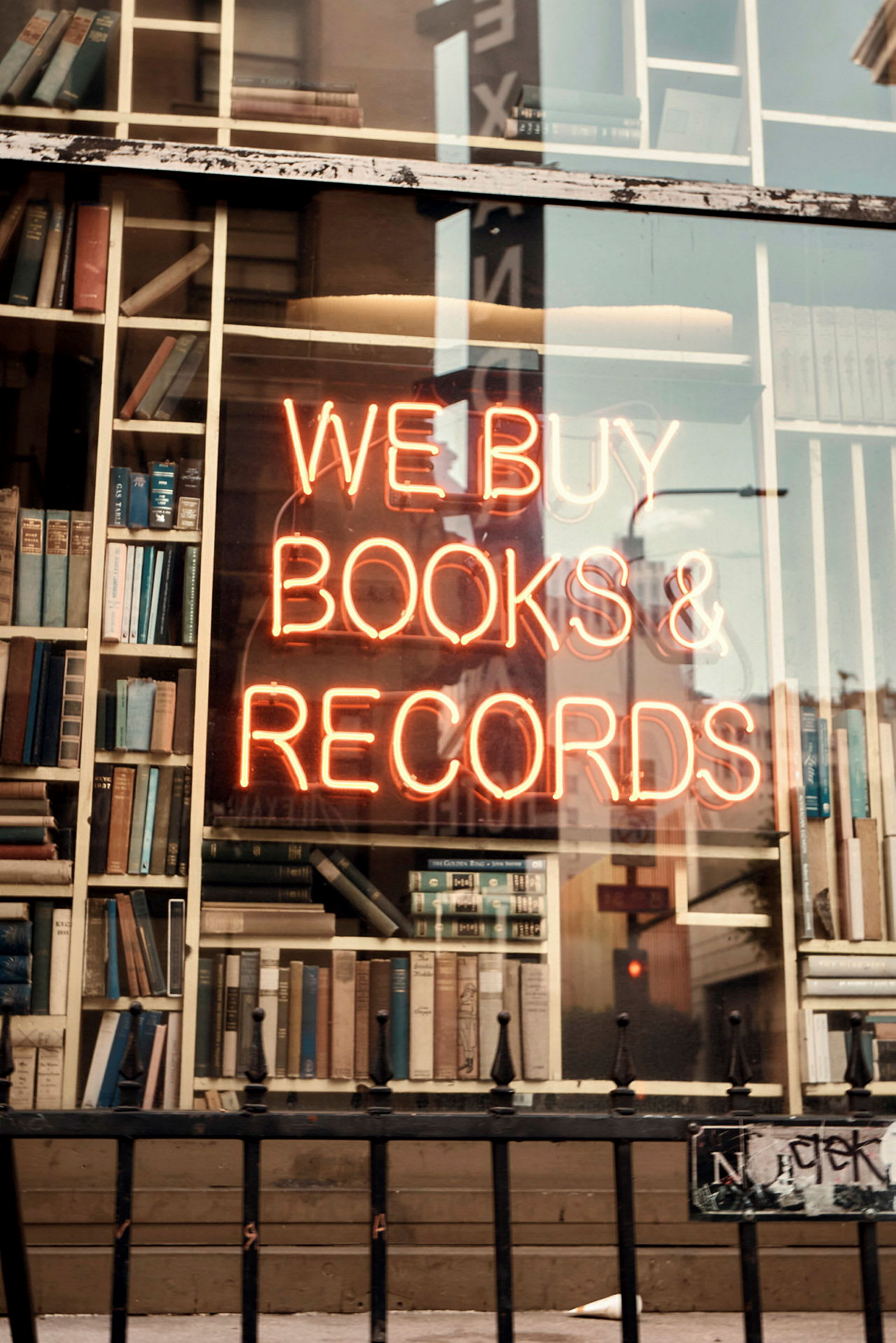 Skyltfönster med böcker och neonskylt som lyder 'We Buy Books & Records'. (AI-genererad text)