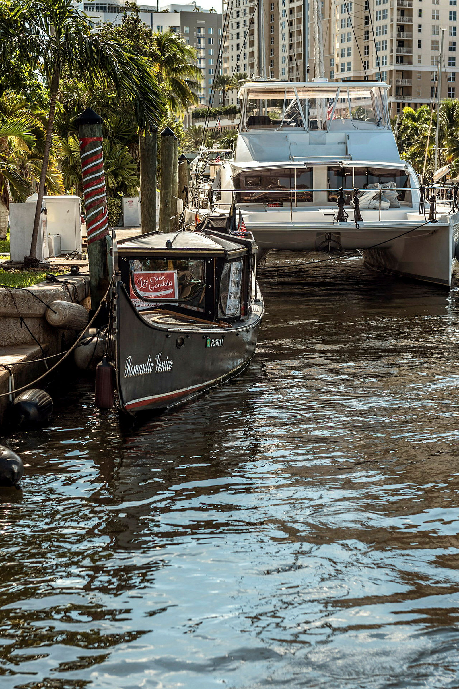 En liten motorbåt och en större yacht ligger vid en kaj i en stad med höghus. (AI-genererad text)
