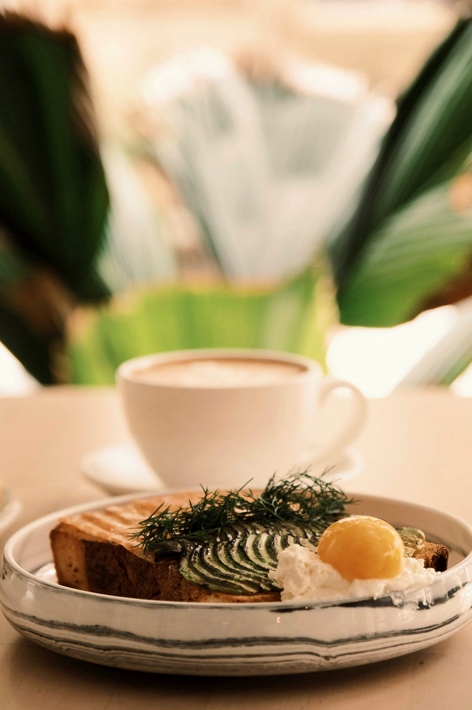 En avokadotoast med gräddfil och ägg serverad bredvid en kopp kaffe. (AI-genererad text)