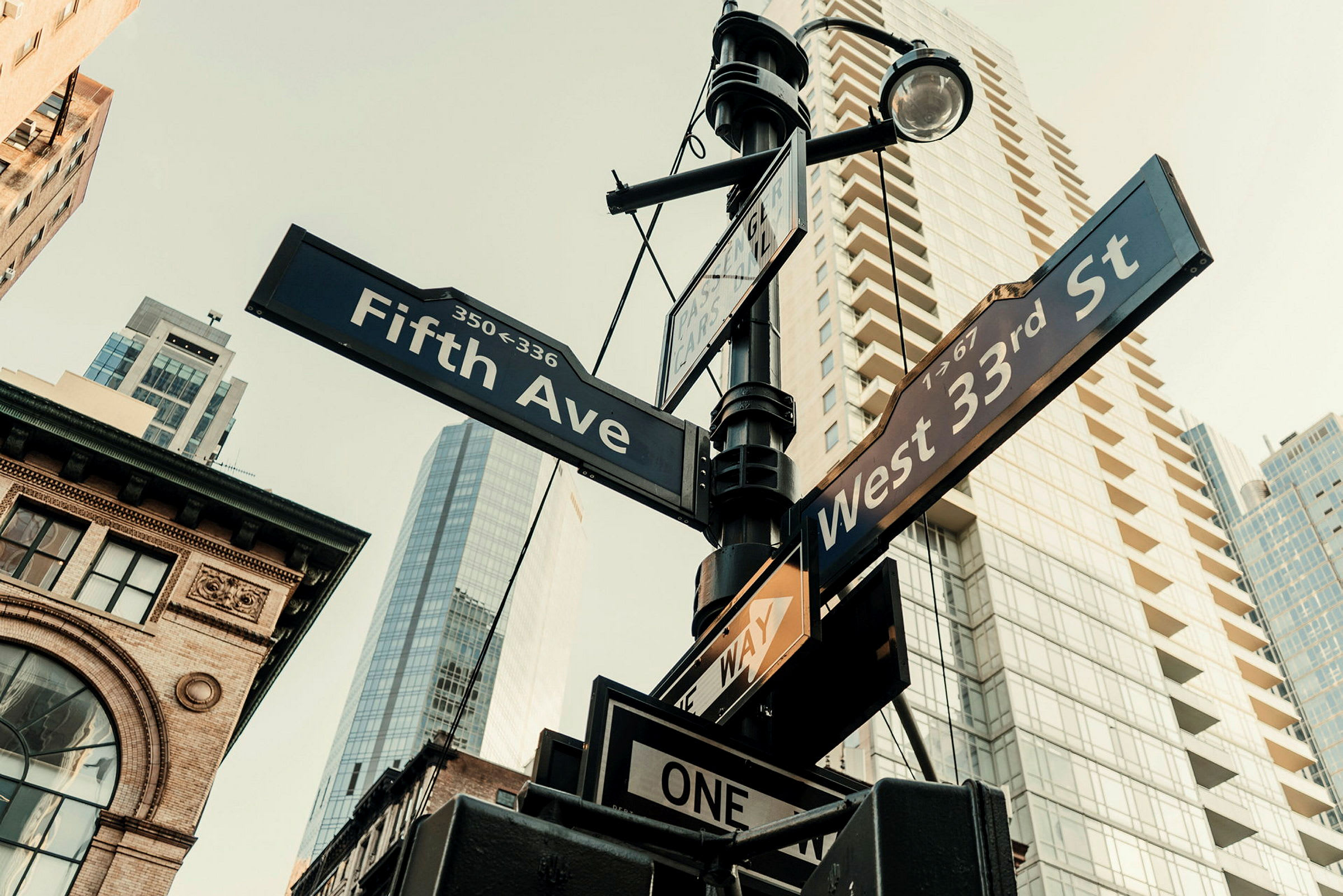 Gatuskyltar för korsningen Fifth Avenue och West 33rd Street i en stadsmiljö. (AI-genererad text)