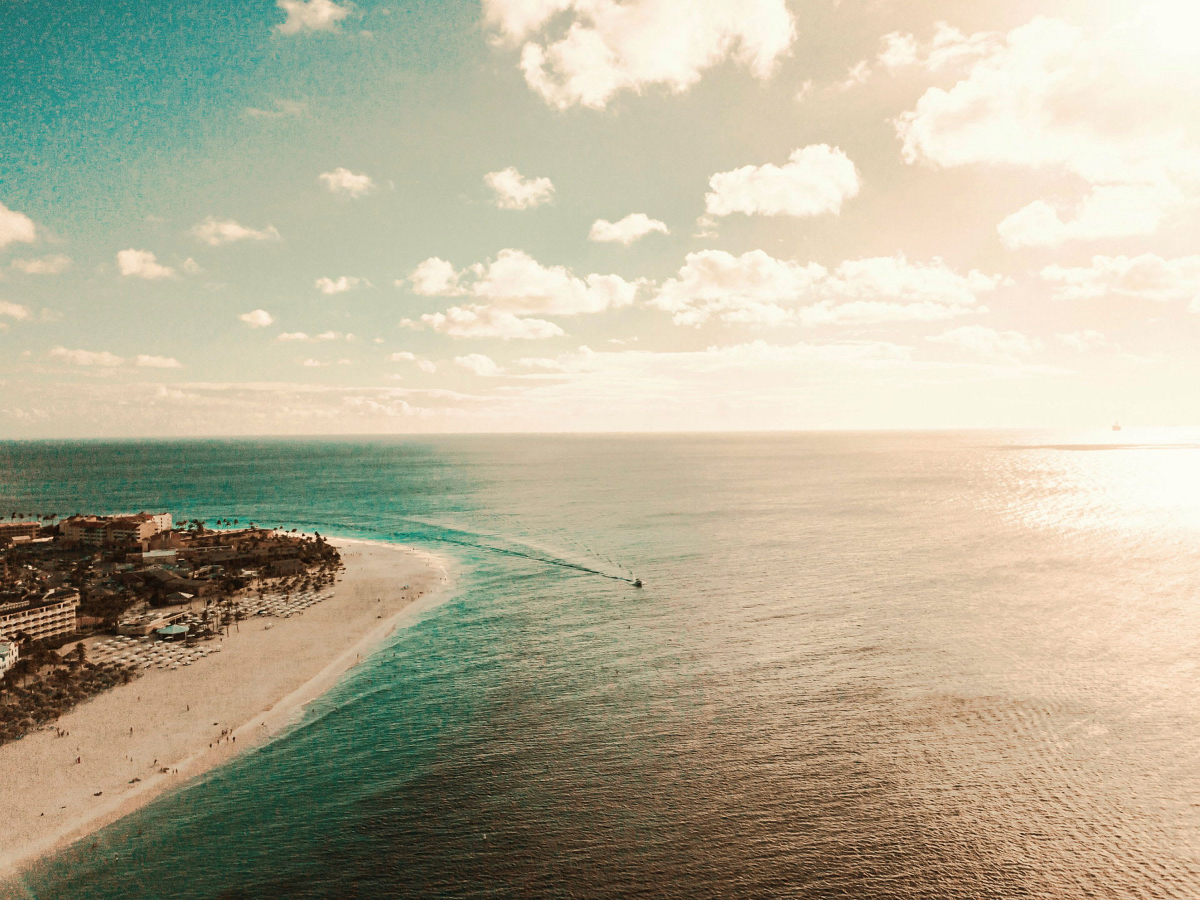 Flygbild av en kust med sandstrand, byggnader och hav. (AI-genererad text)