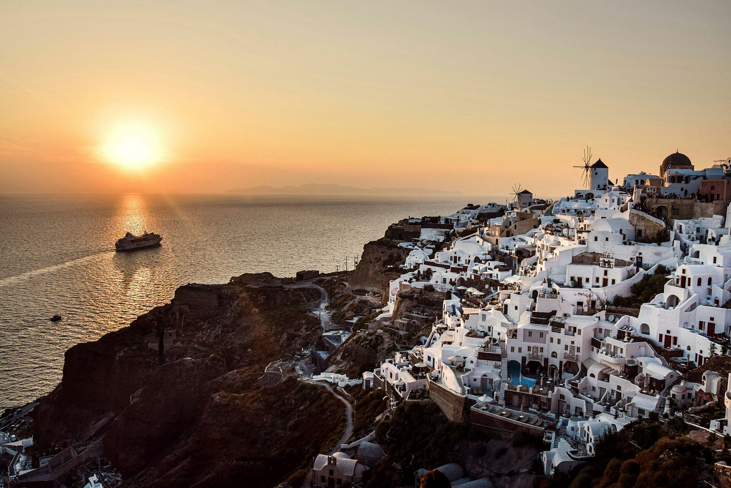 Utsikt över vitkalkade byggnader i Santorini vid solnedgången, med havet i bakgrunden. (AI-genererad text)