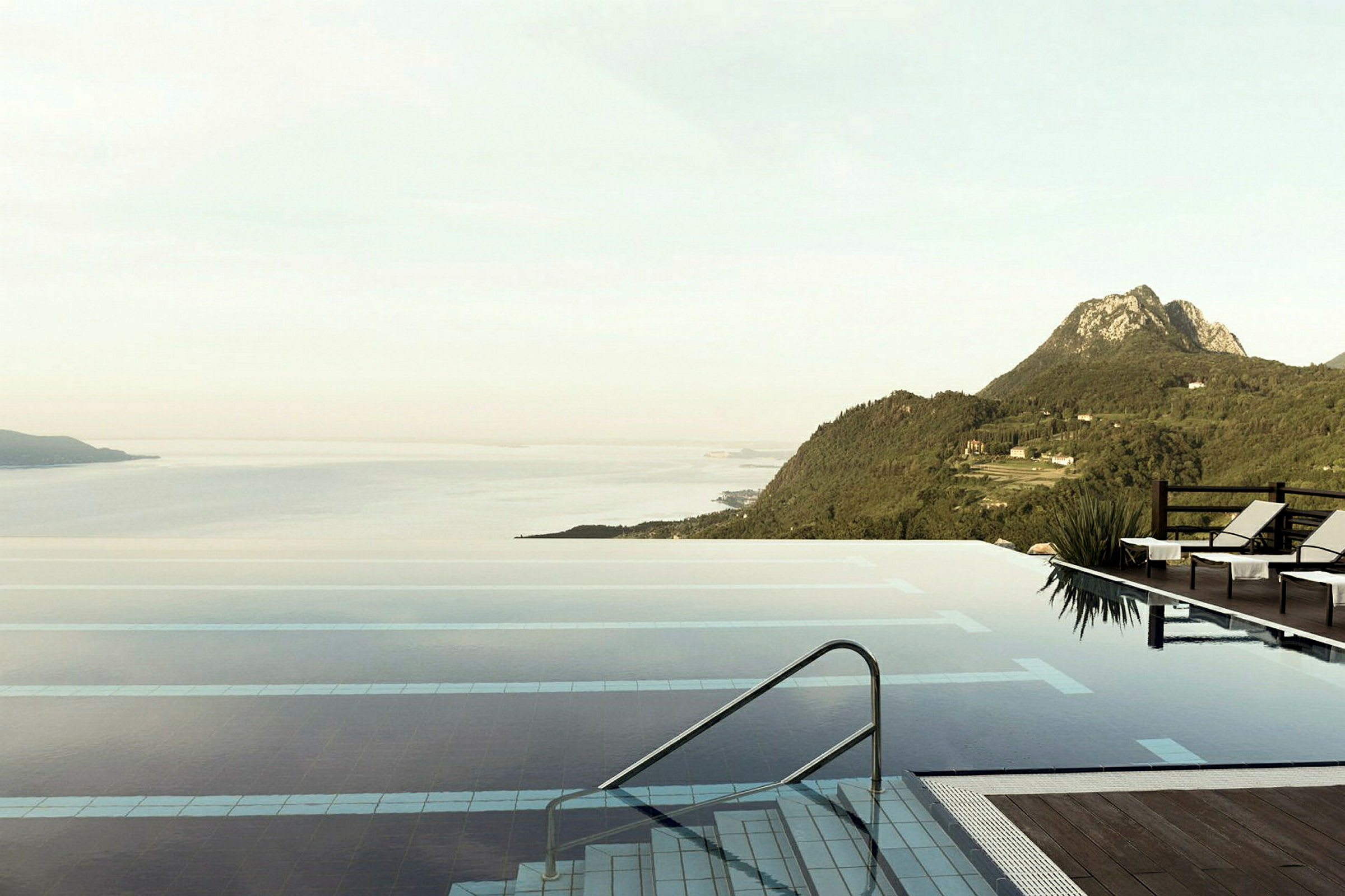 En infinitypool med utsikt över en bergig kustlinje med en lugn havsvy. (AI-genererad text)