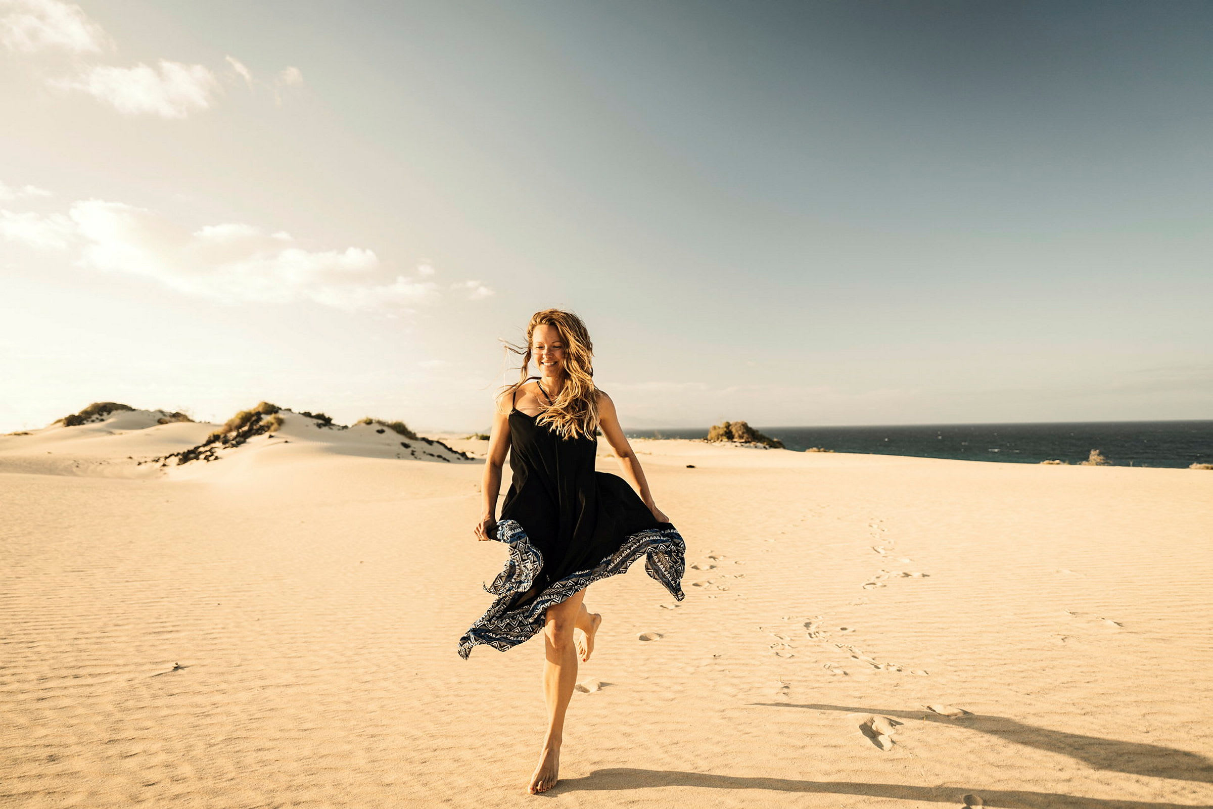 En person går på en sandstrand med havet och himlen i bakgrunden. (AI-genererad text)